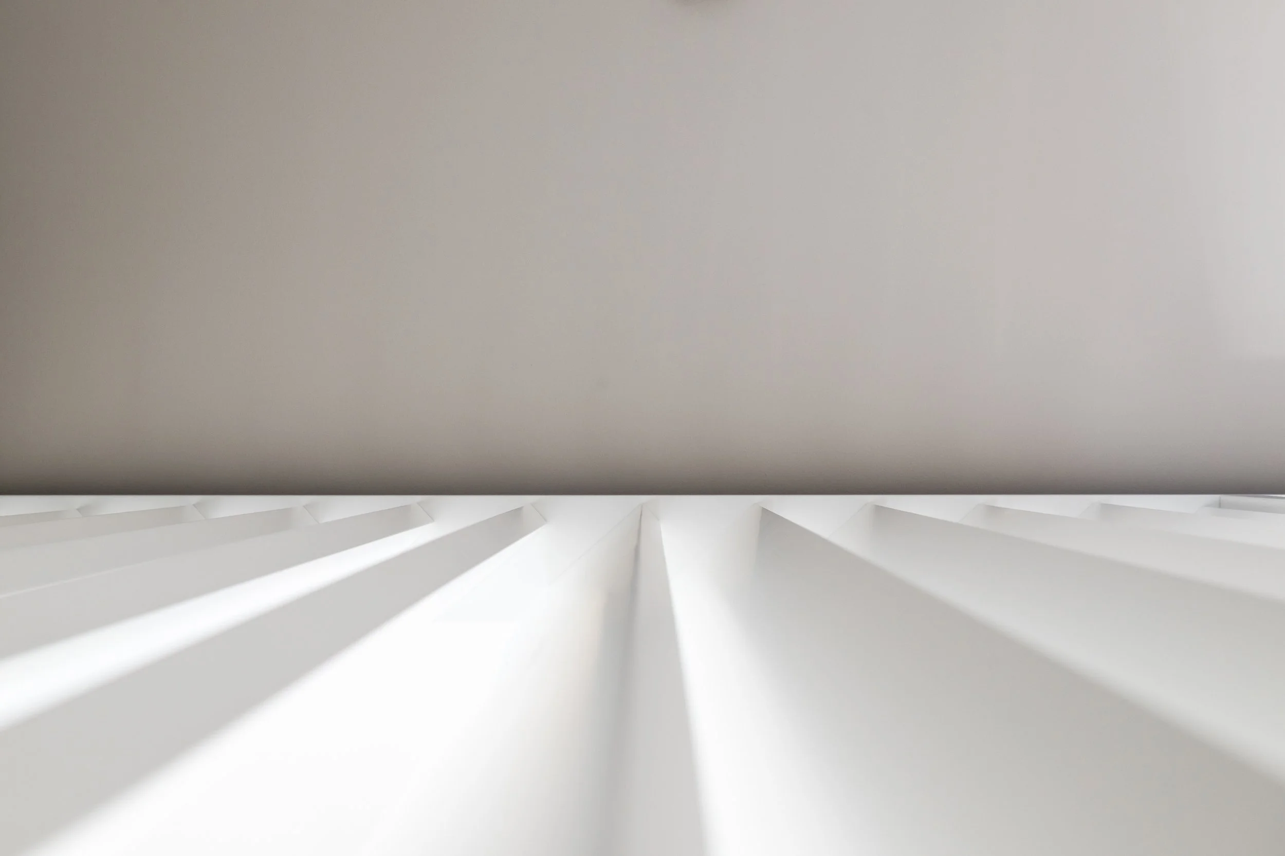 Dettaglio del brise-soleil laccato bianco progettato come elemento filtro tra cucina e soggiorno. Le lame verticali definiscono una soglia permeabile che mantiene la continuità visiva e spaziale dell’appartamento Ink a Palermo.