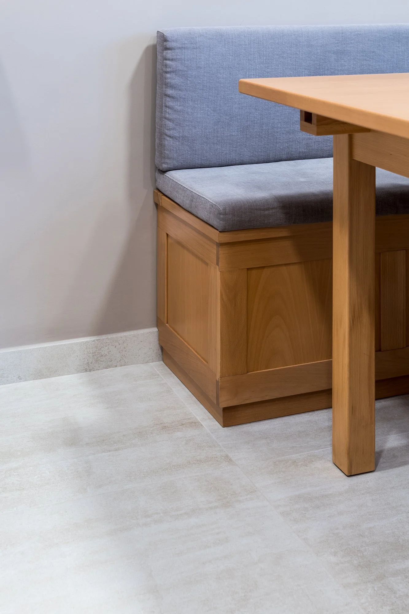 Dettaglio della zona pranzo con seduta su misura in legno, rivestimenti in gres porcellanato e palette cromatica neutra. Nel progetto Mikado a Palermo materiali, superfici e arredi integrati contribuiscono alla costruzione di uno spazio domestico equ