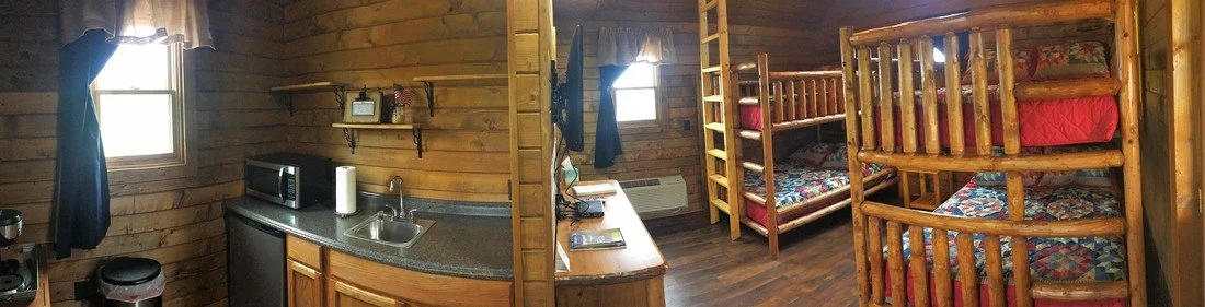 Interior of a rustic cabin with a small kitchen and wooden bunk beds