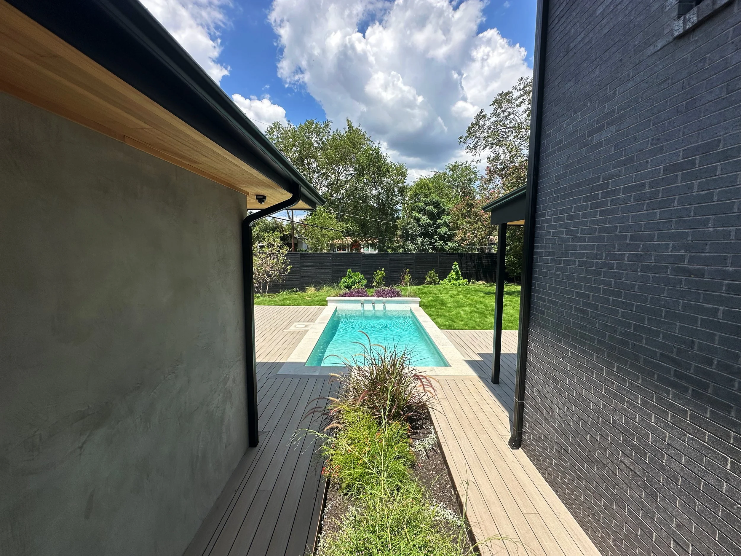 Modern pool viewed down a planted passage with native Austin ornamental grasses between house walls
