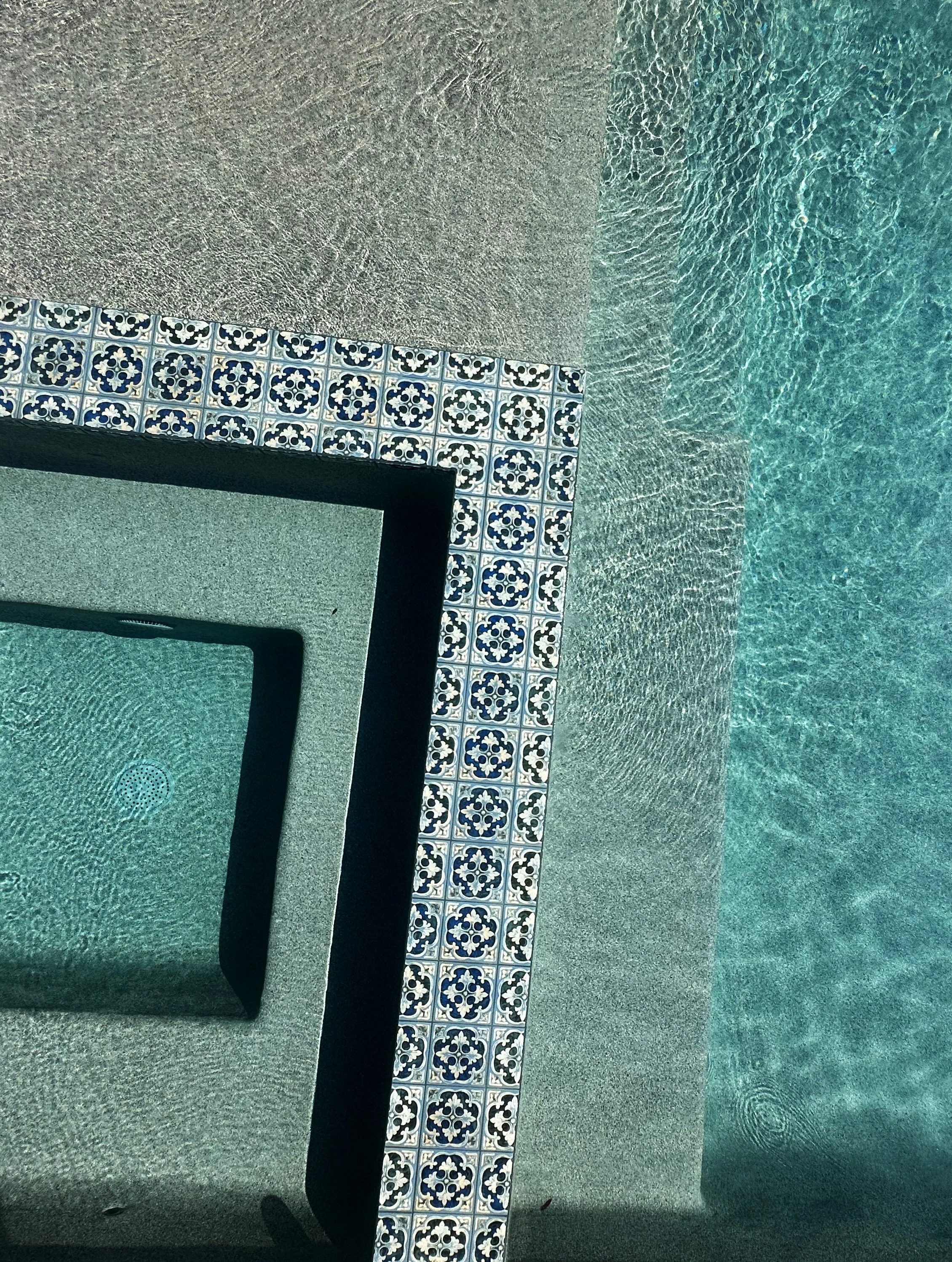 Close-up of NPT Hana Capri Spanish tile and French Gray pebble interior on a flush spa