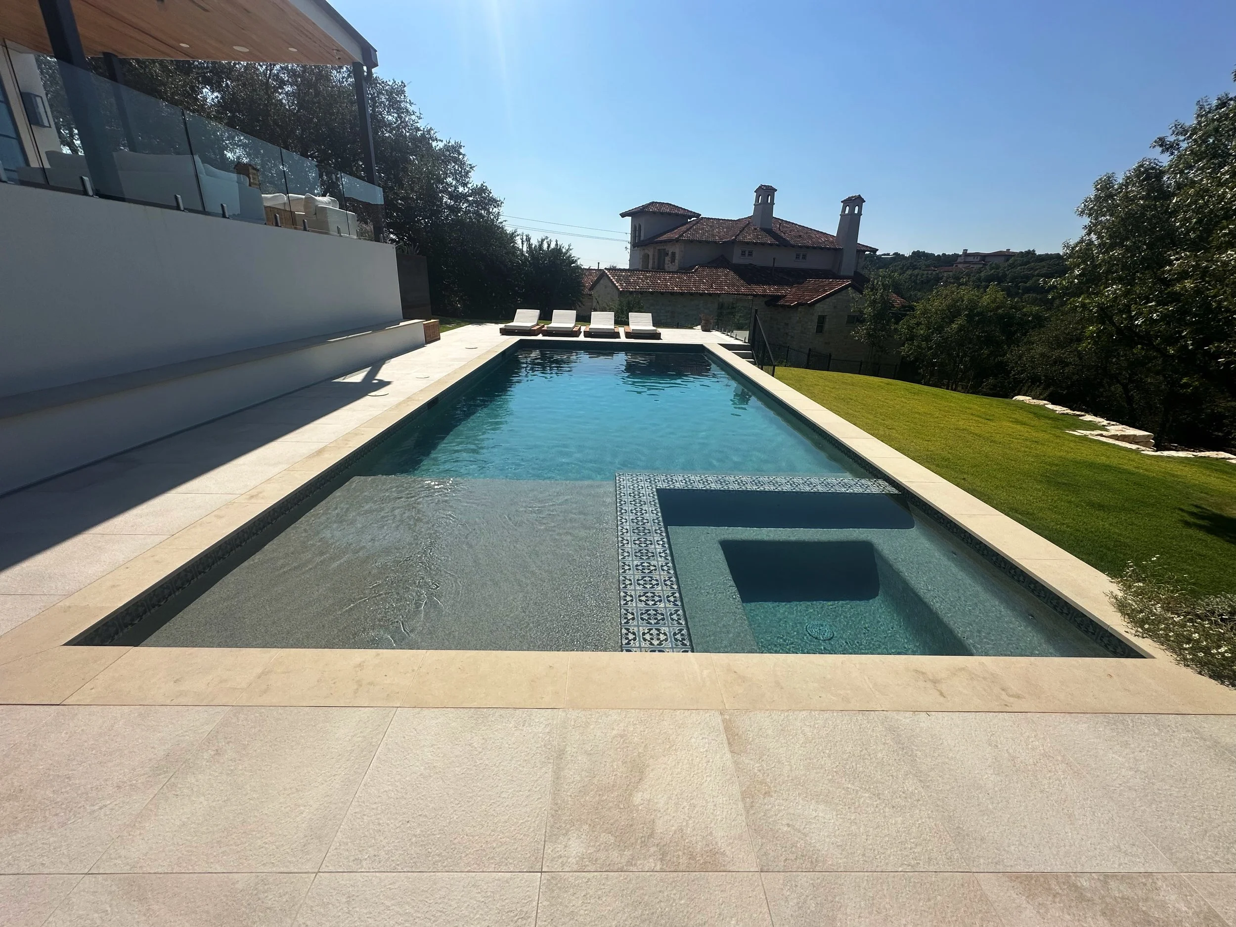 Modern luxe pool with flush spa and tanning ledge framed by Hill Country views