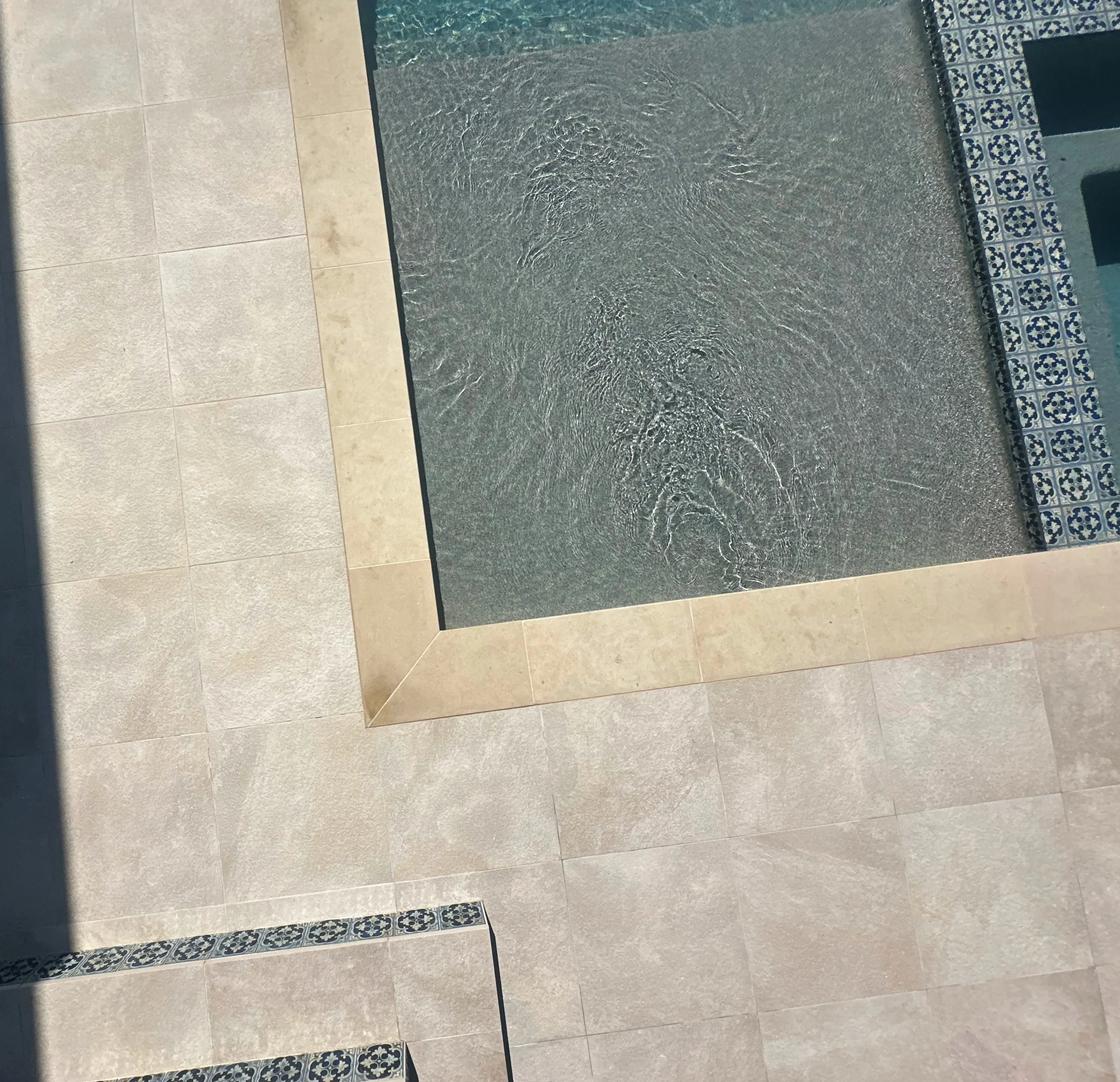 Overhead view of a pool sun shelf, buff Lueders coping, and Spanish tile spa steps