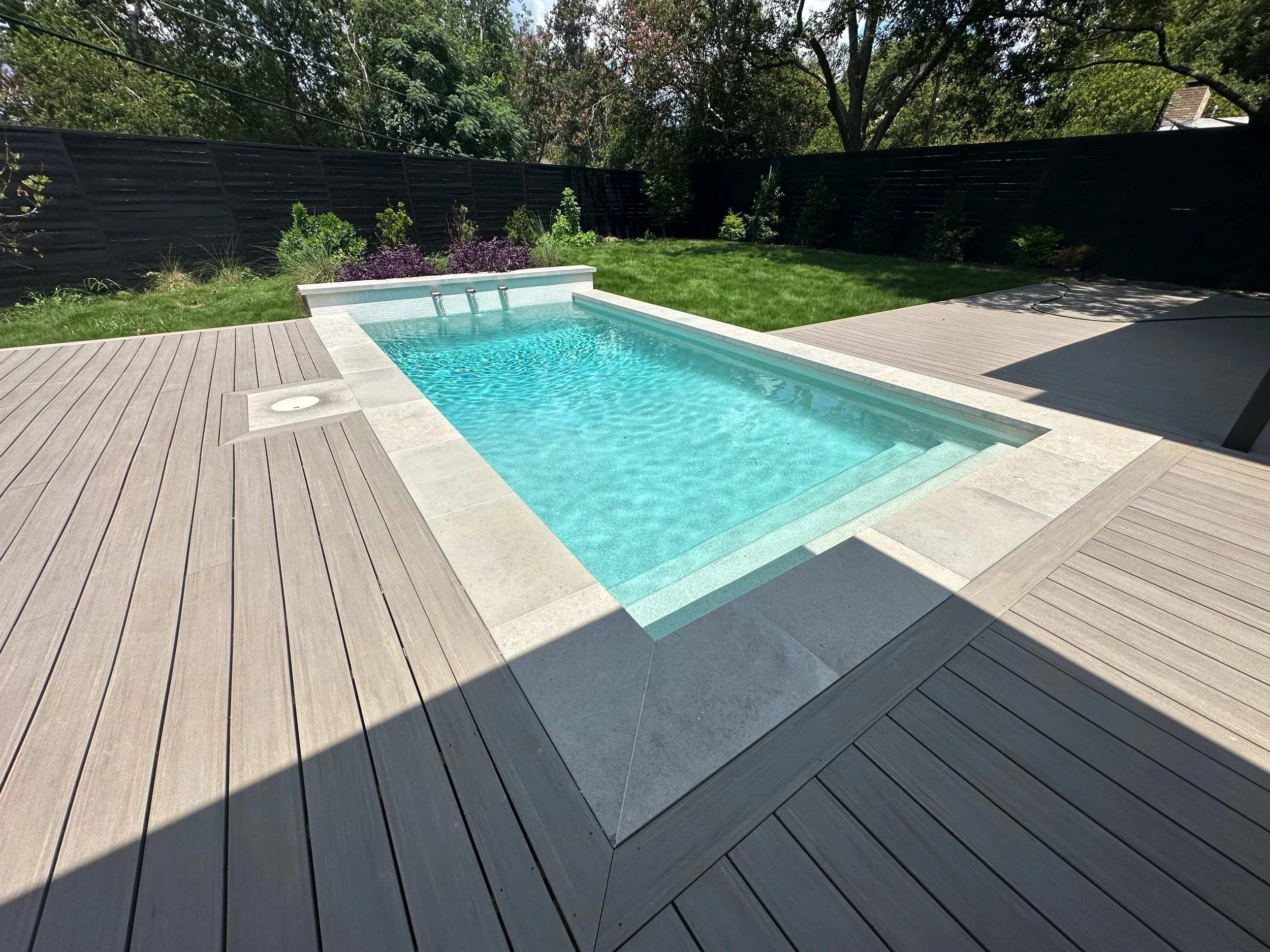 Modern pool with Charcoal Lueders coping set into a wooden composite geometric deck
