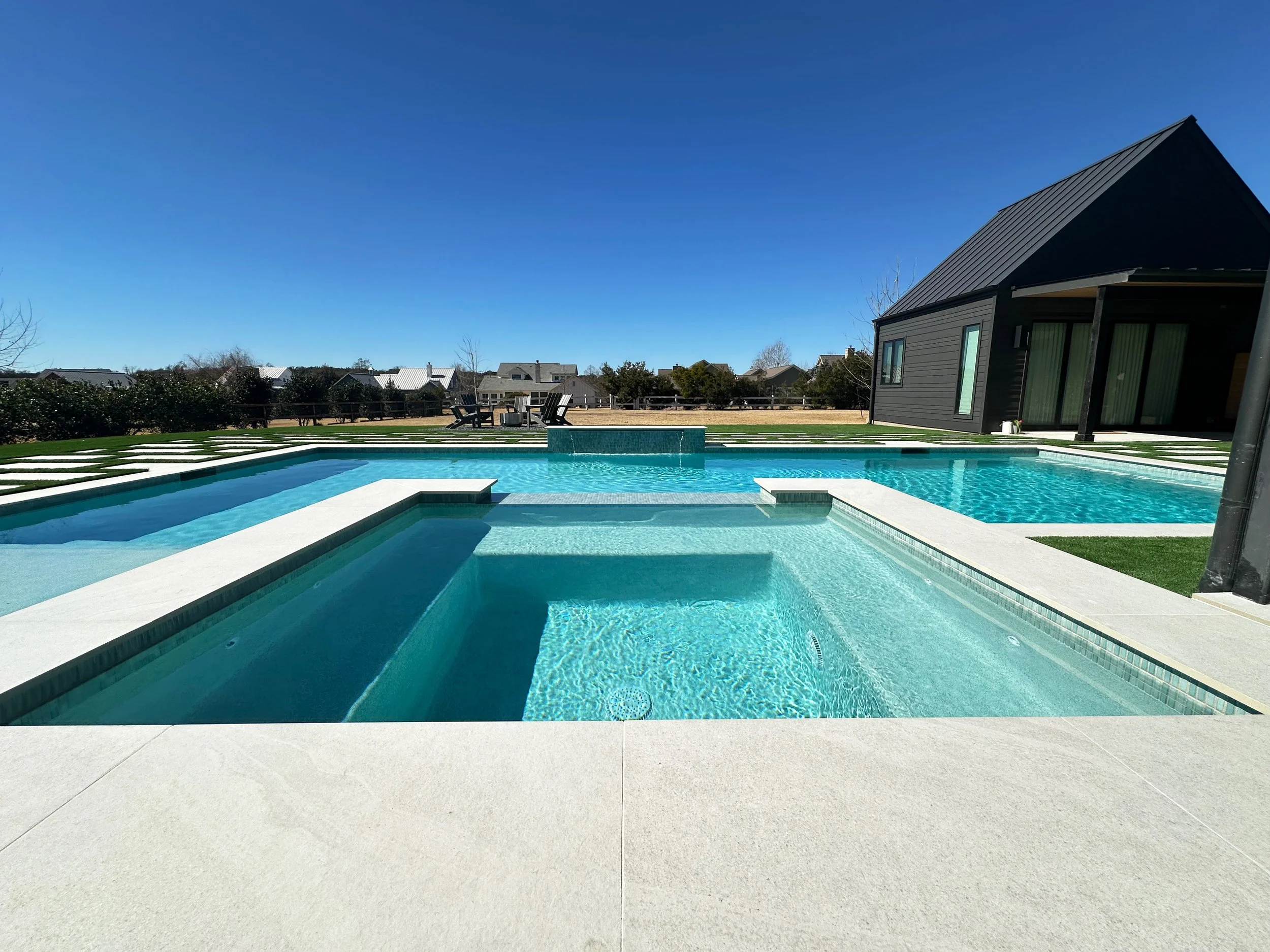 Modern farmhouse pool and raised spa with turf-and-paver deck, casita, and firepit lounge