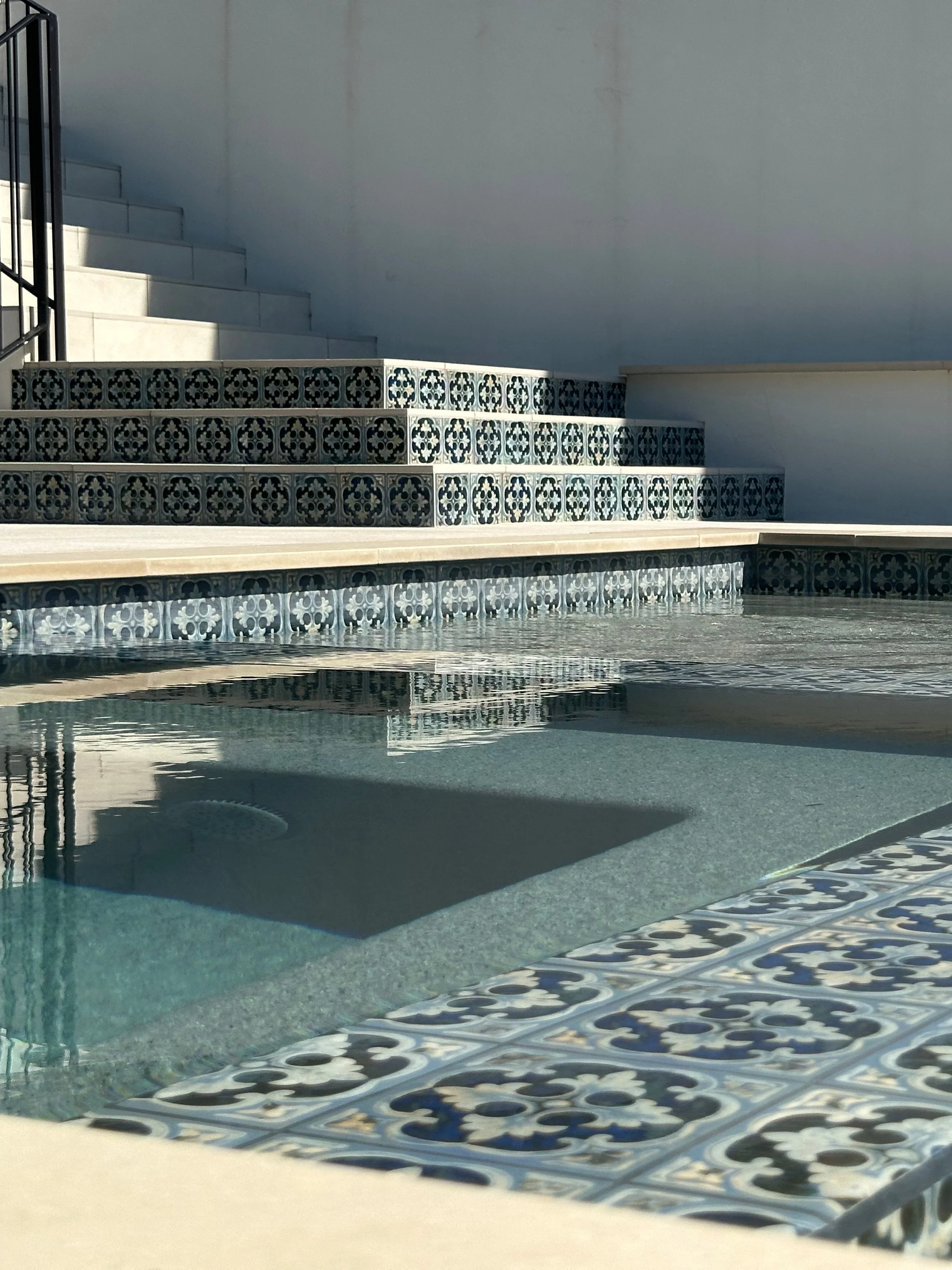 Pool spa with tiled bench seating and Hana Capri tile steps below a modern home