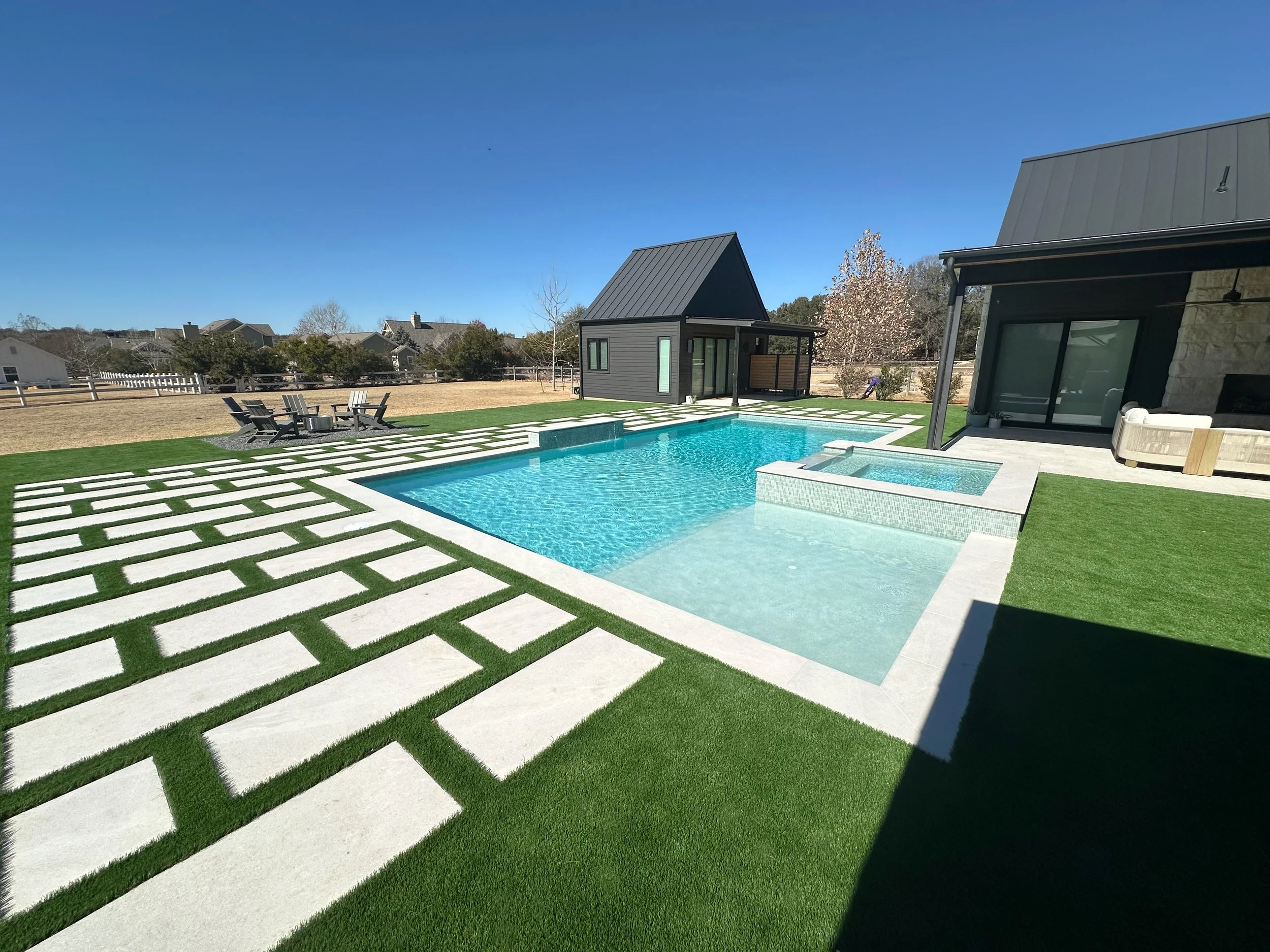 Modern farmhouse pool and raised spa with paver-and-turf deck, casita, and Adirondack firepit lounge
