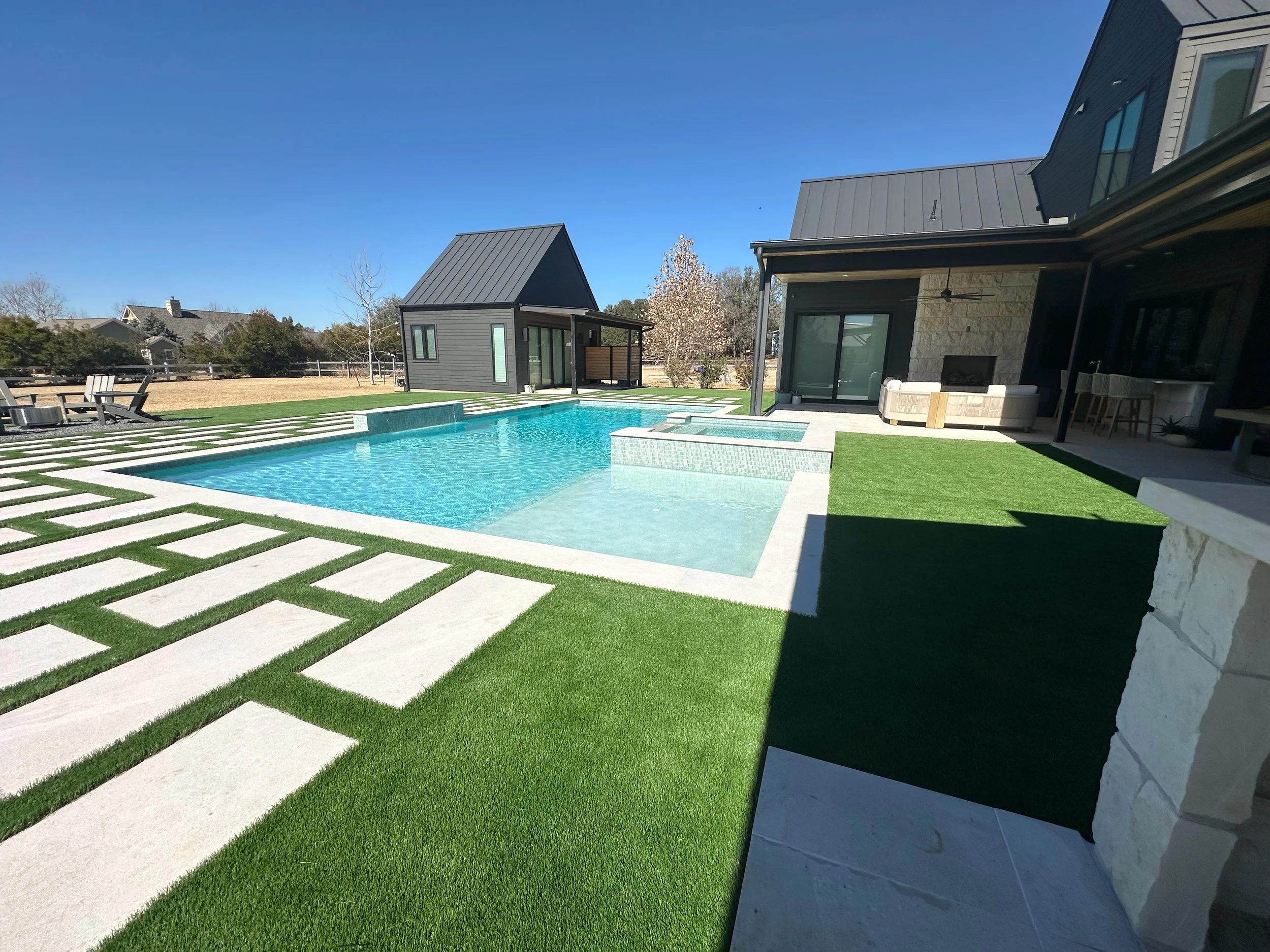 Modern farmhouse pool and raised spa with TurfGro Two Tone 84 turf-and-paver deck and firepit lounge