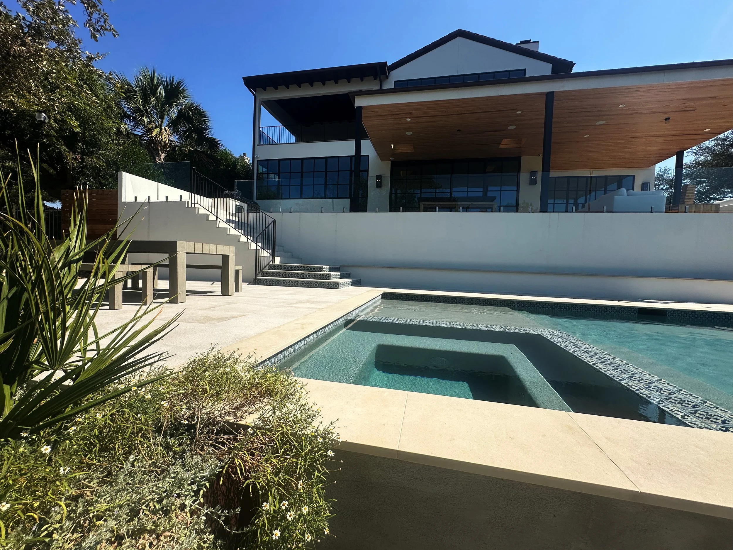 Contemporary Austin home with a modern luxe pool, flush spa, and buff Lueders stone deck