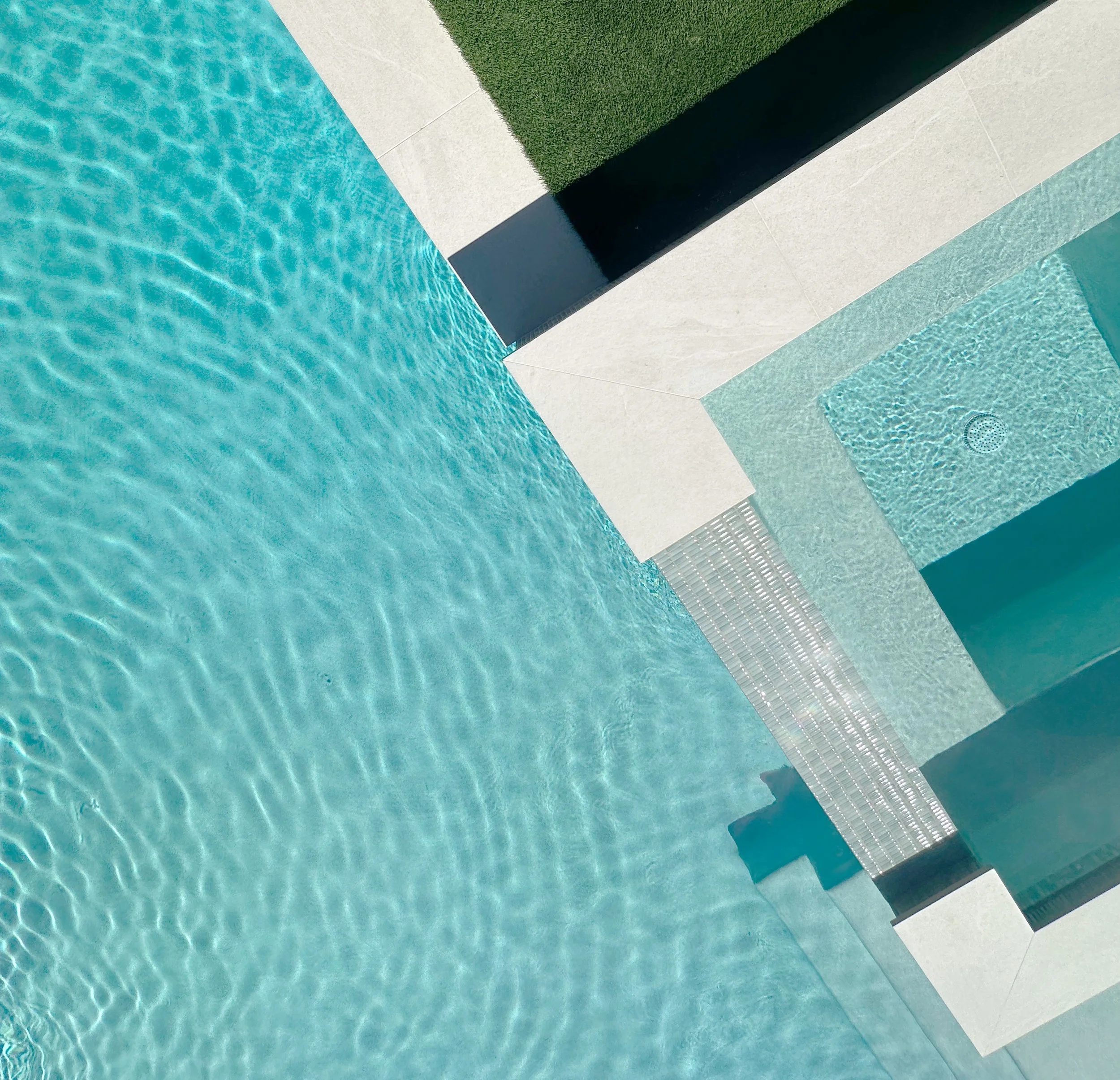 Overhead of a raised spa and spillover flowing into an NPT ColorScapes Cayman Green pool