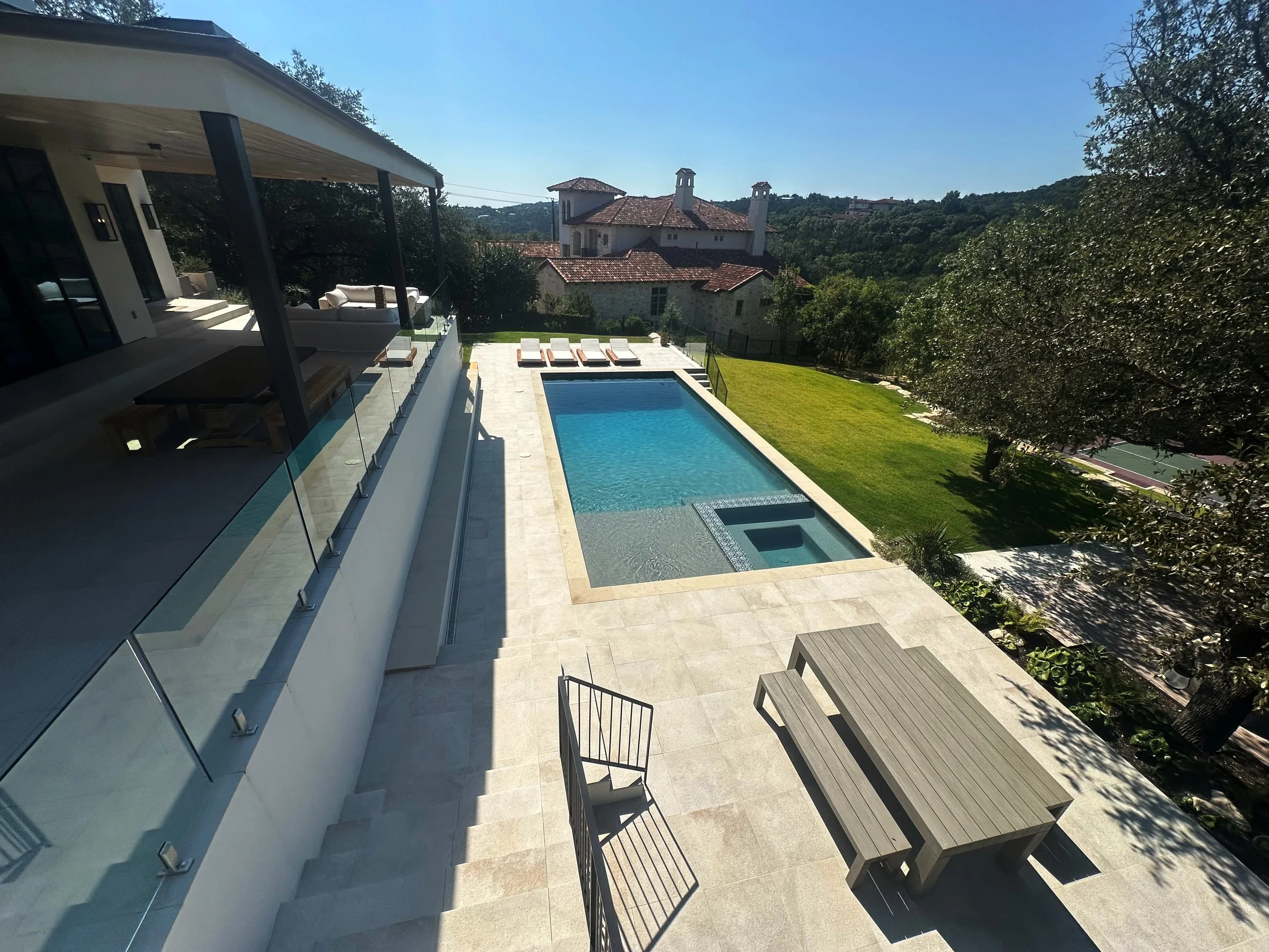 Elevated view of a modern luxe pool, spa, and buff Lueders deck in the Austin Hill Country