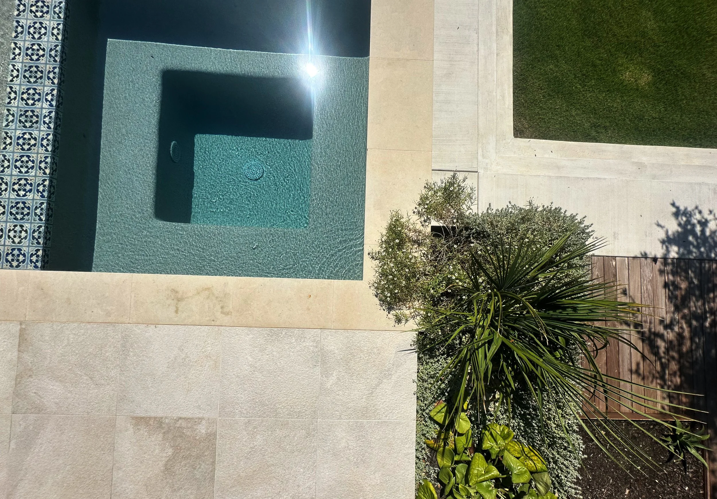 Aerial view of a flush spa with blue Hana Capri tile beside native Hill Country landscaping