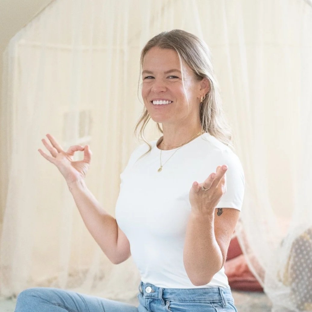 Ashley Stresen-Reuter smiling and sitting in a bright room doing a yoga pose
