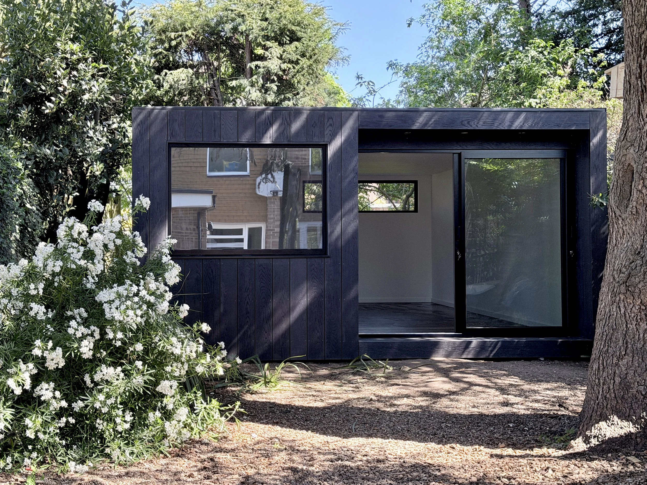 Bespoke multi-use garden room with matte black cladding, large windows and sliding glazed doors.
