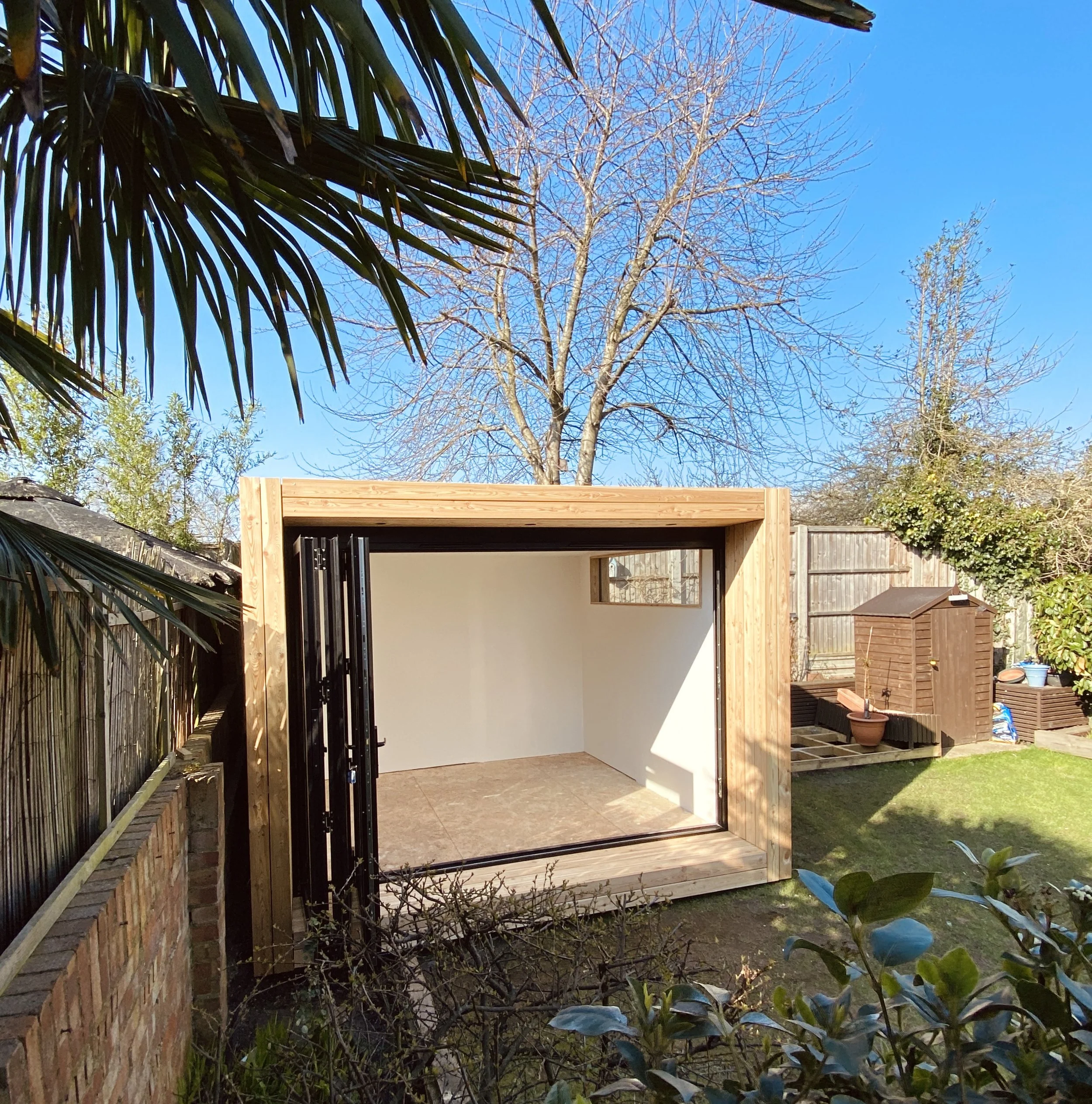Front view of the NEO garden studio with large double-glazed doors open, showing the light-filled interior space