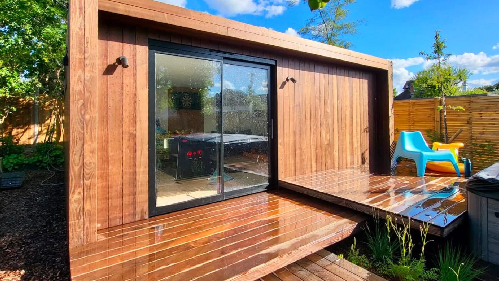 Made-to-measure timber-clad garden room with sliding glass doors and a raised decking area.