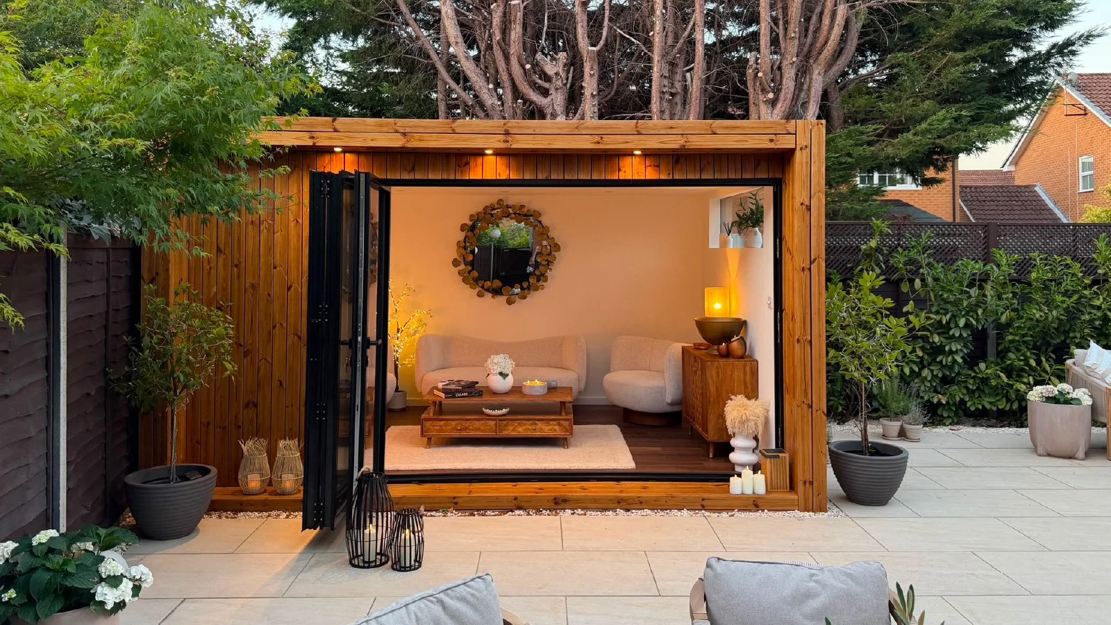 Bespoke garden entertainment room with open bi-fold doors, comfortable seating and a fully finished interior.