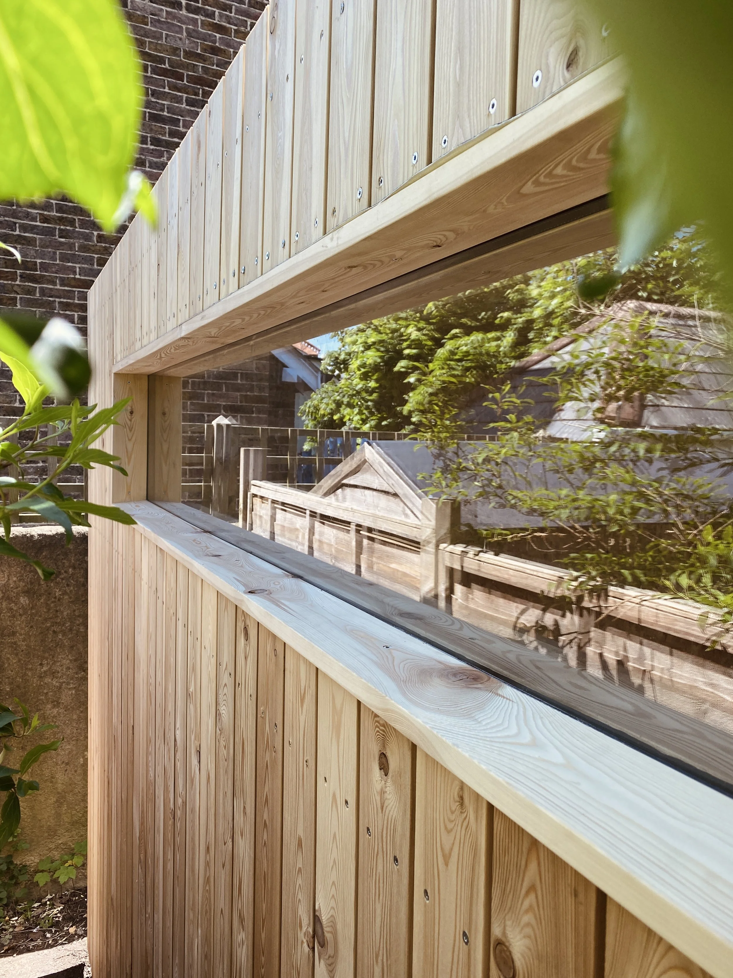 Exterior detail of the NEO garden studio showing the fixed double-glazed window, windowsill, and Larch cladding