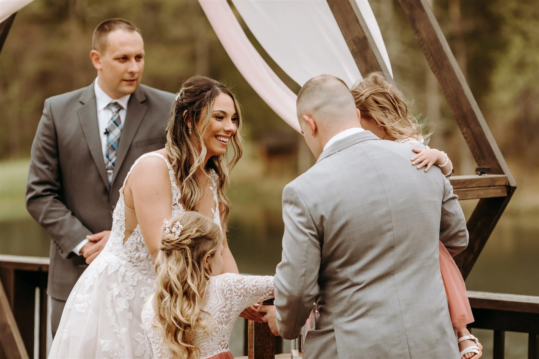 A wedding ceremony outdoors with a bride, groom, one child at Rolla, Missouri rustic wedding venue, The Village. Photos by Columbia, MO Photographer Liv Strange Photography.