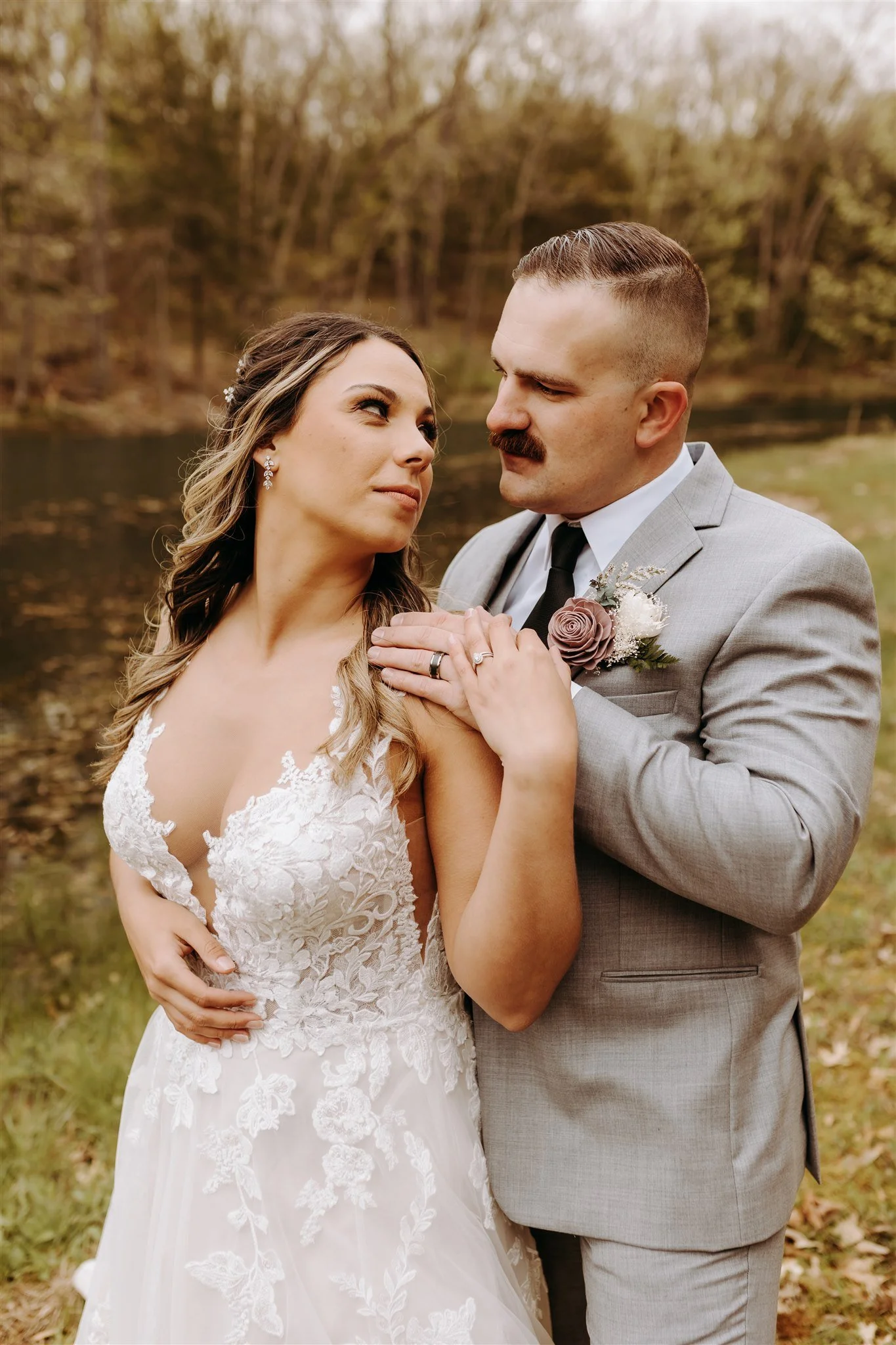 A bride and groom close together outdoors near a body of water with trees in the background at Rolla, MO rustic wedding venue, The Village. Photos by Columbia, MO Photographer Liv Strange Photography.