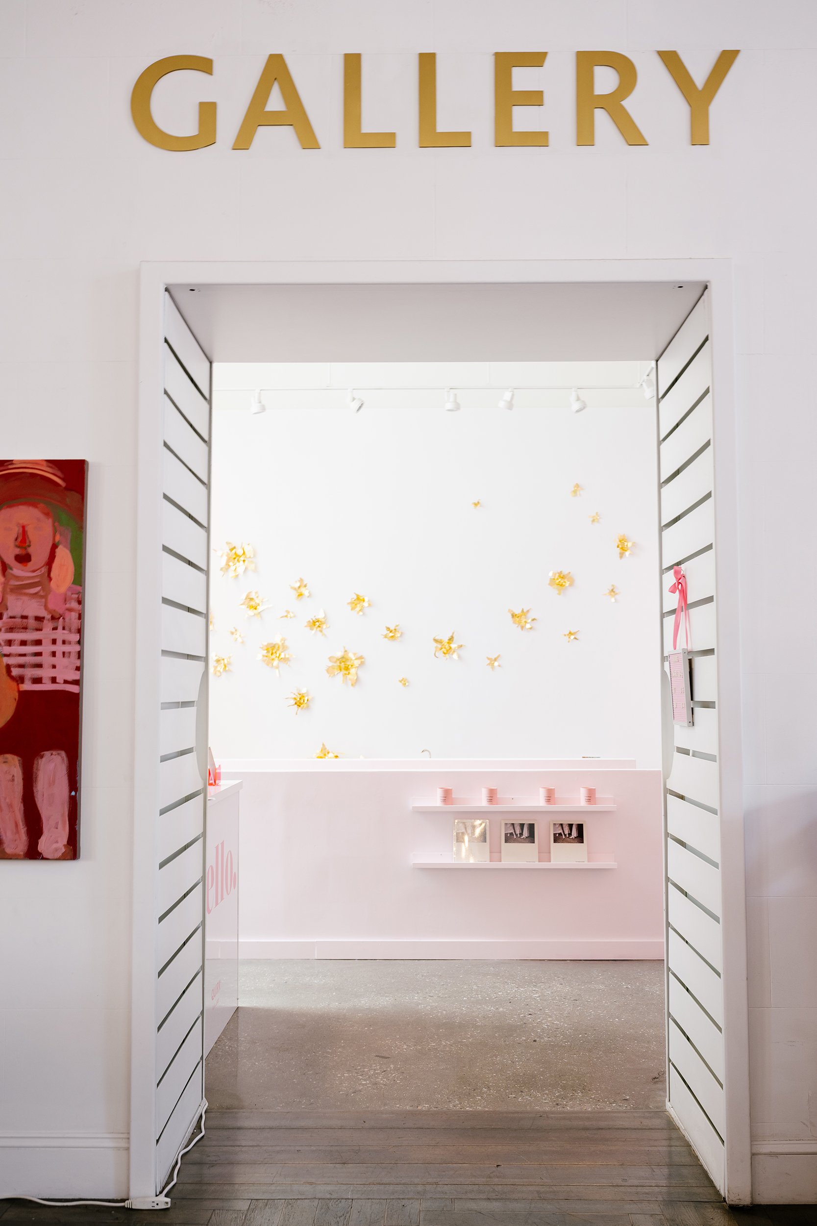 A white wall decorated with multiple gold-colored metal flowers arranged in clusters.