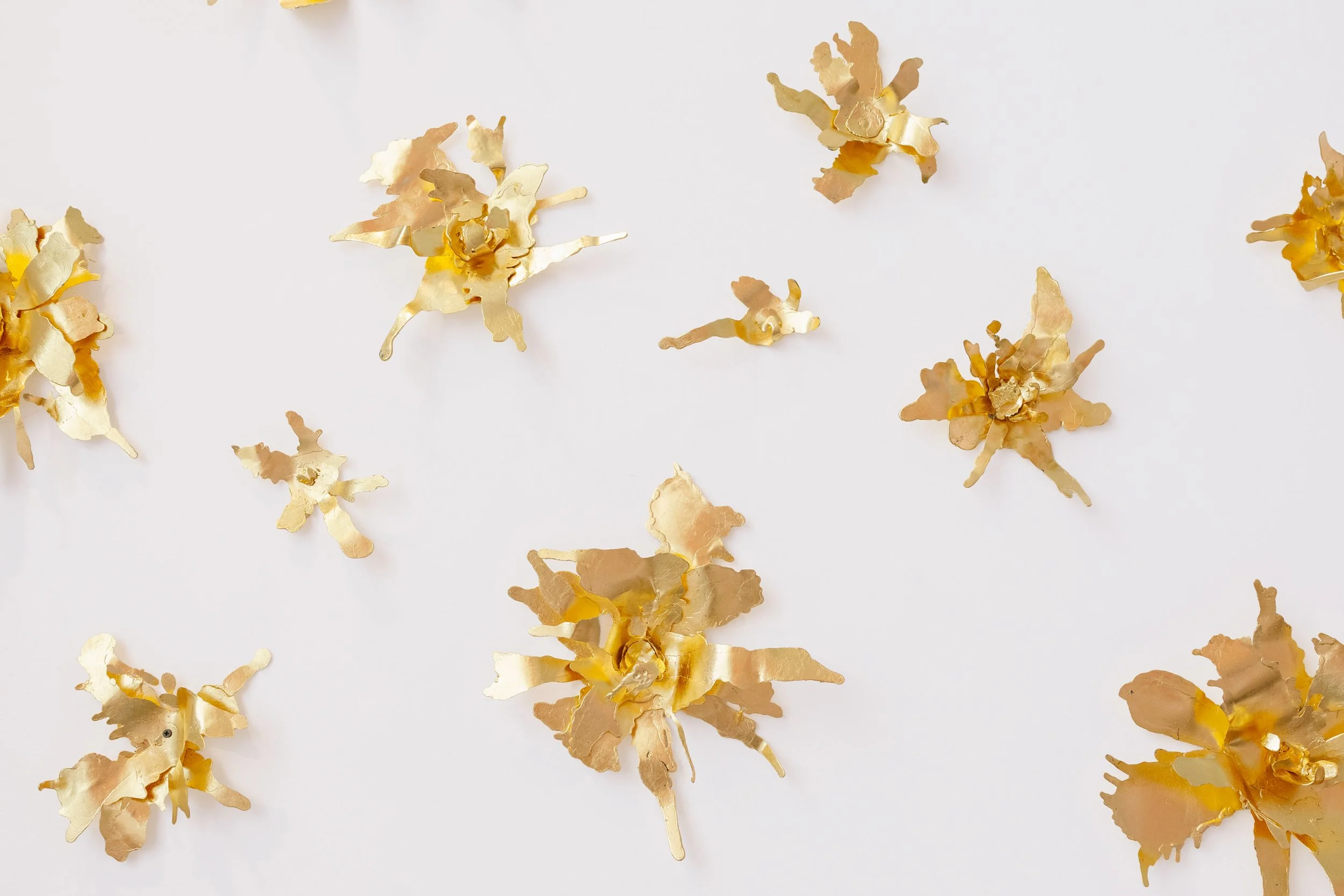 Gold metallic flower-shaped confetti scattered on a white surface.
