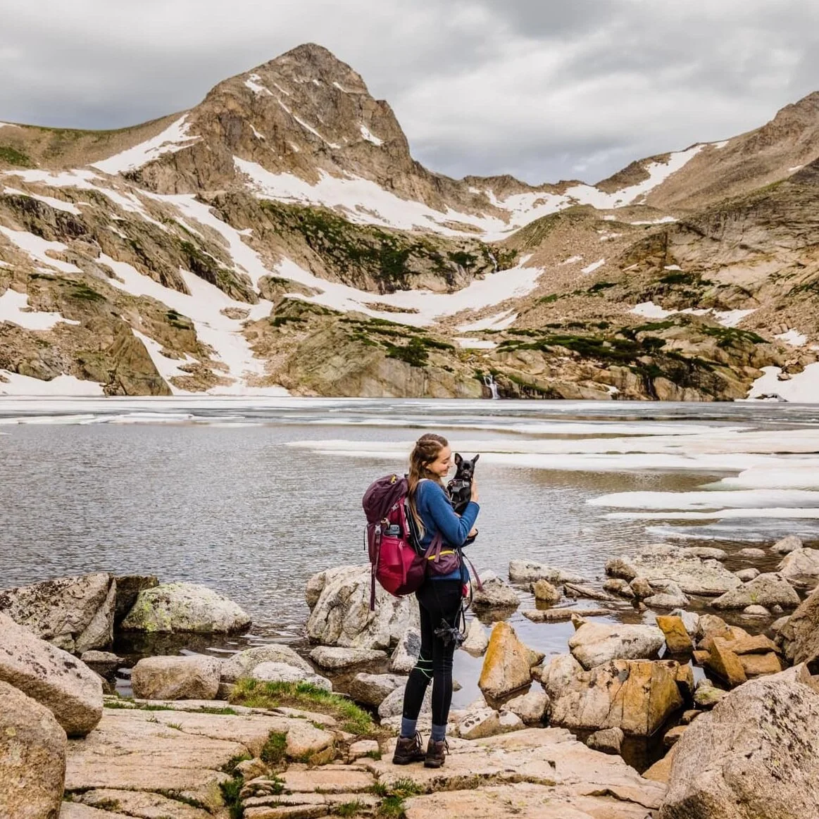 Lisa holds her chihuahua on a hike in the mountains.
