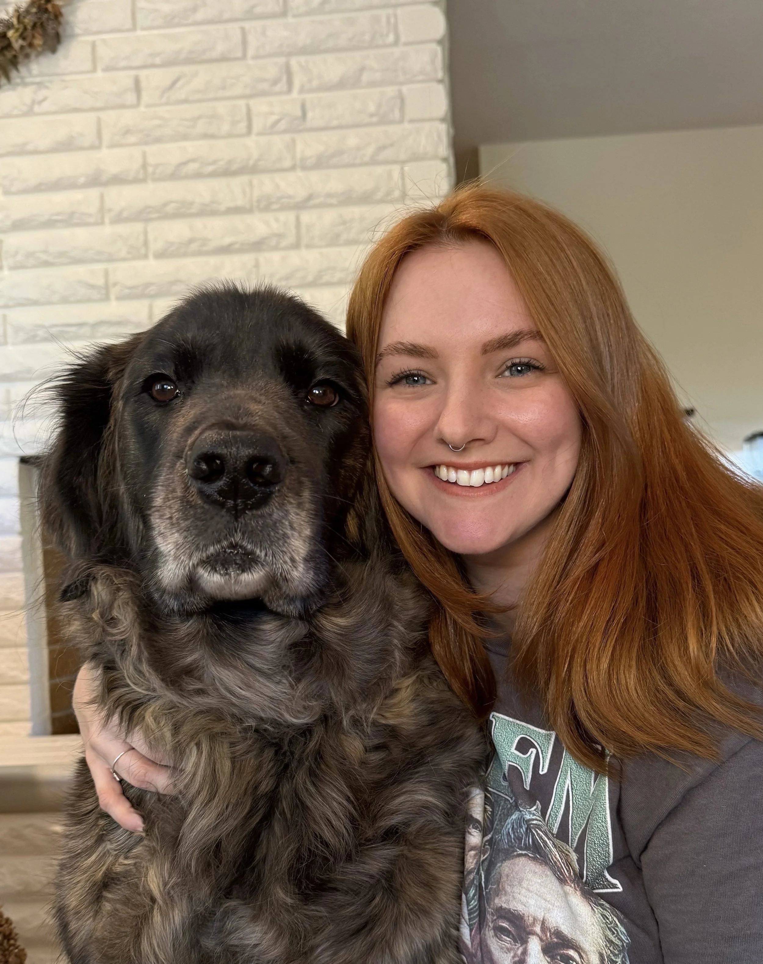 Mo smiles and poses for the camera with a black and brown dog.