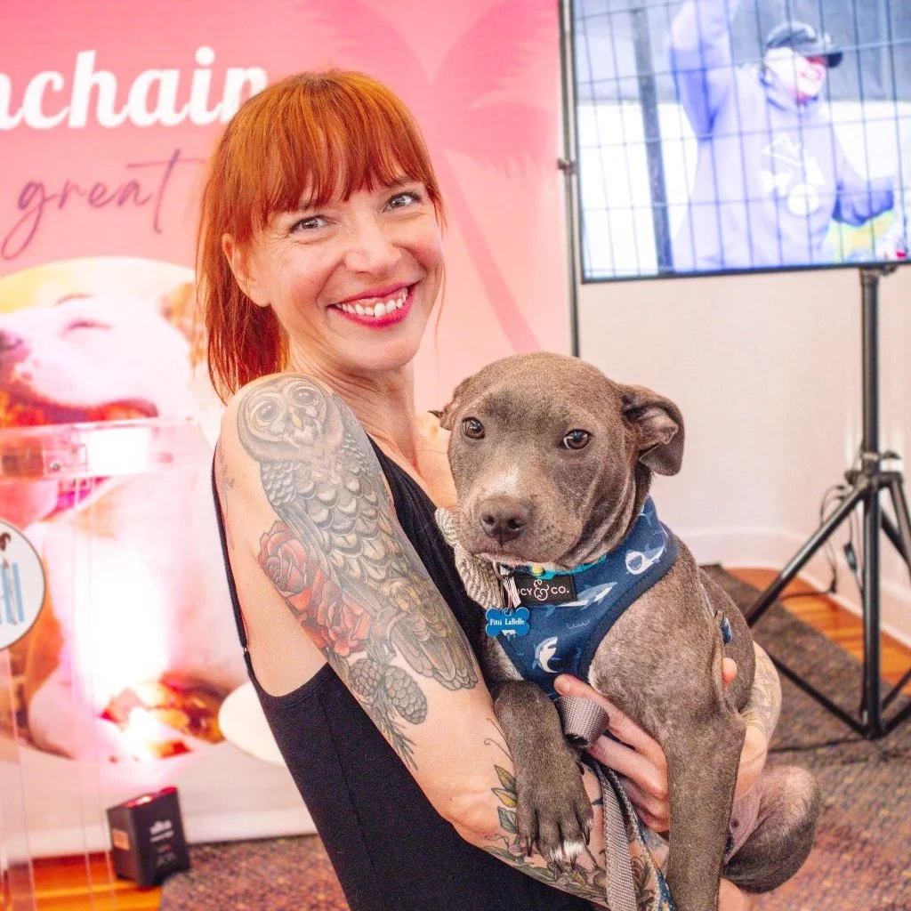 Becky holds a gray puppy in her arms.