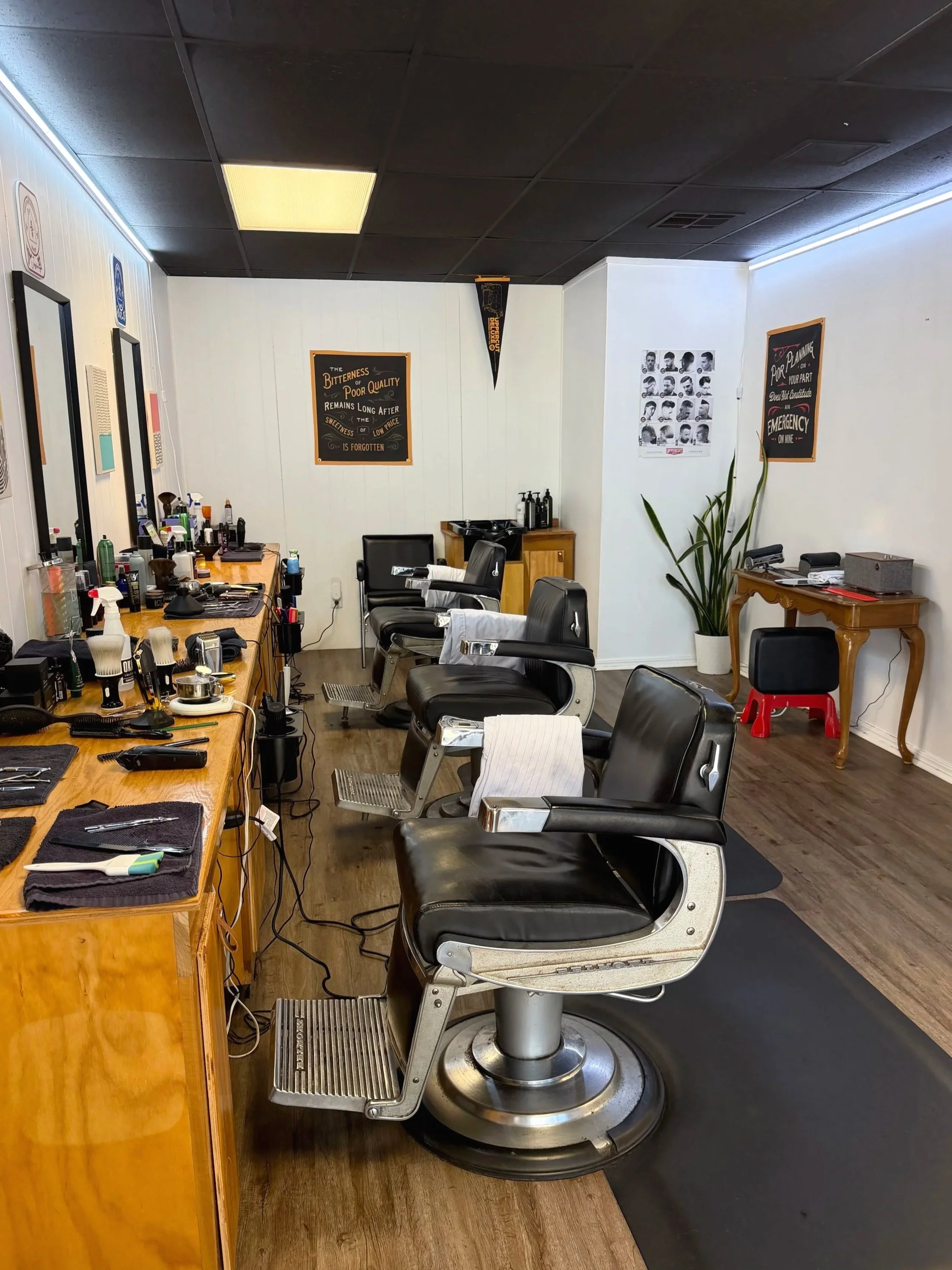 Clean, quaint barber shop with chairs, mirrors, and barber tools on the counter.