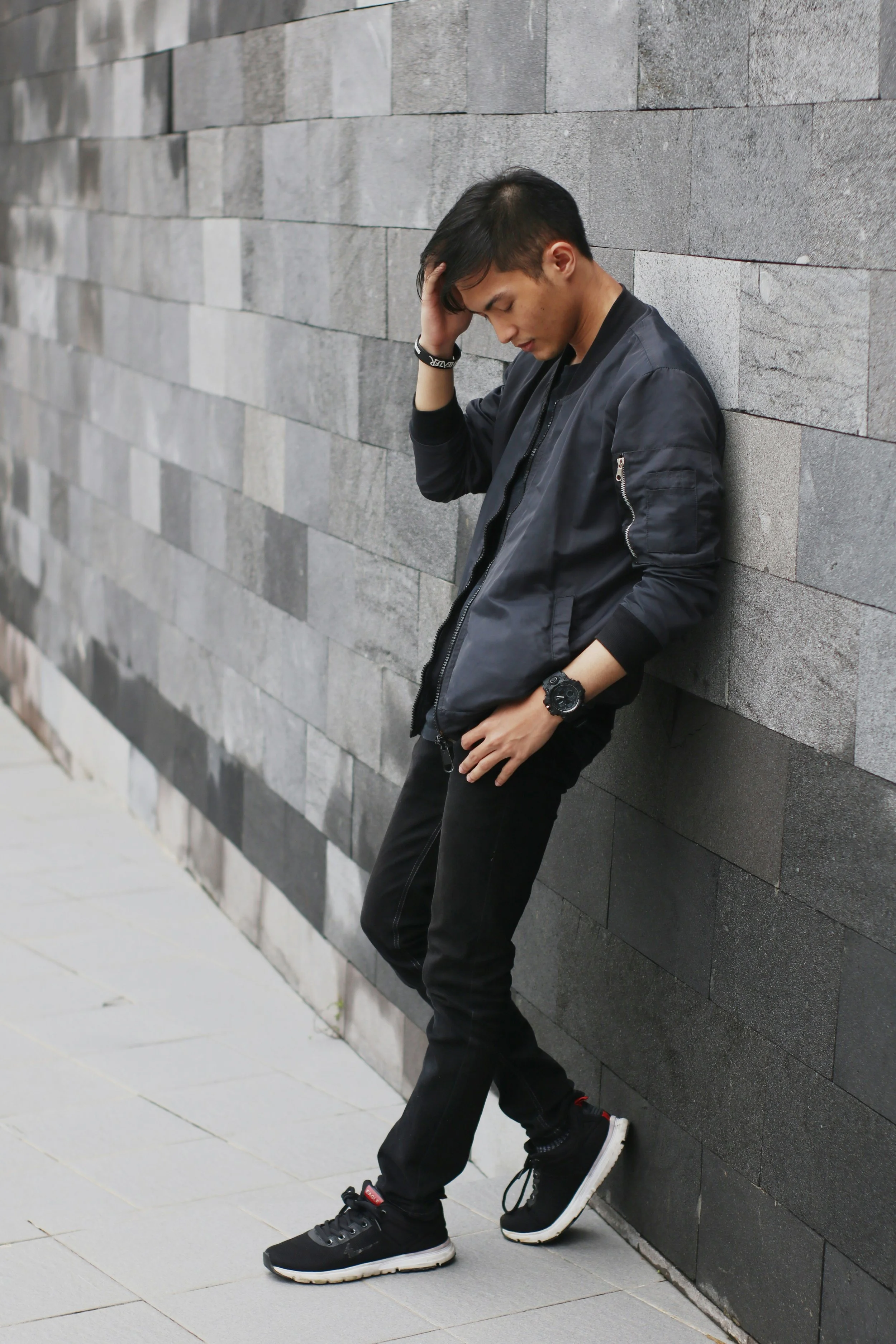 Man leaning against a gray wall looking stressed, symbolizing anxiety and emotional struggle before starting trauma therapy in Seattle
