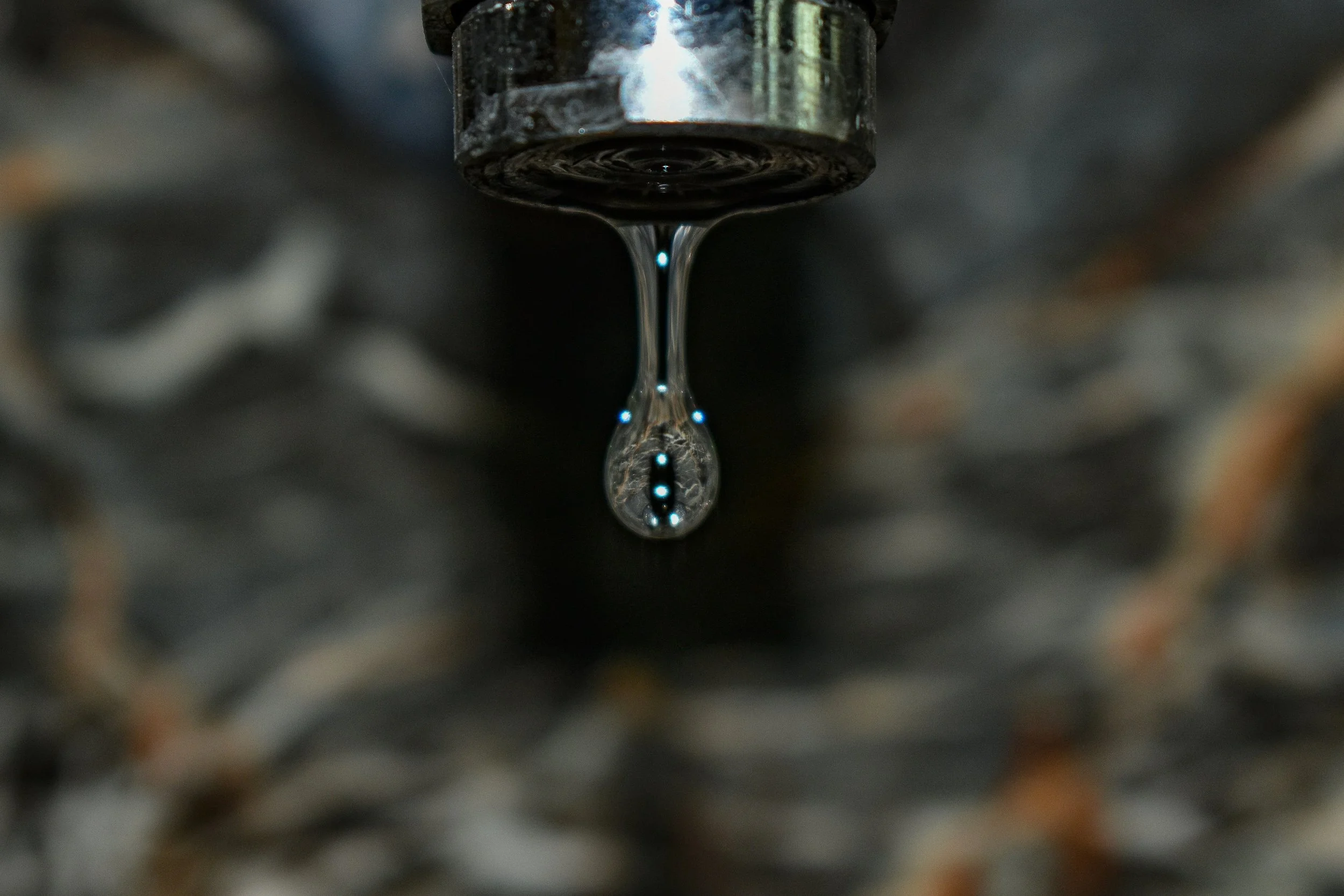 Photo of a drop of water out of a faucet indicating the slow drip of childhood trauma.