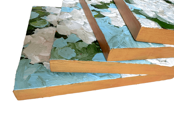 Side view of set of 4 paintings of white flowers on thick wood