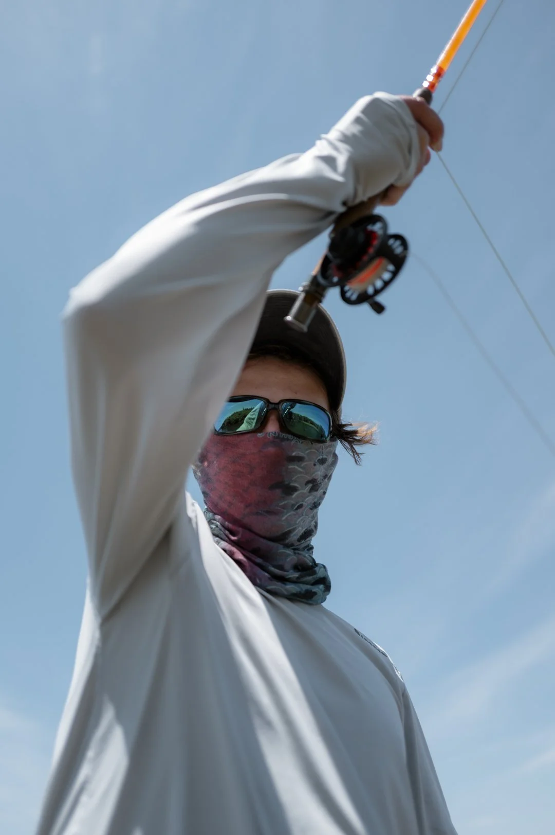 Person fishing with a casting rod outdoors on a sunny day.