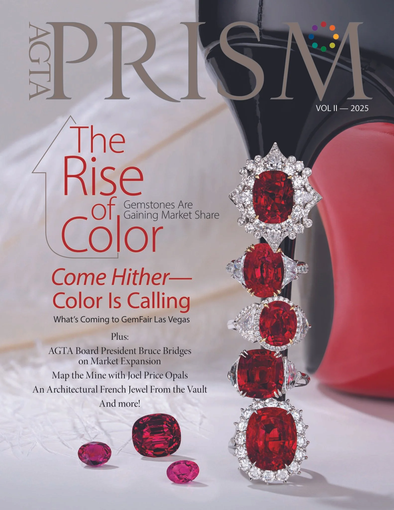 The cover of a magazine titled 'Prism', Volume II, 2025. The main headline reads 'The Rise of Color'. The cover features a close-up of a luxurious ring with several large red gemstones surrounded by clear diamonds. Several loose gemstones, both pink 