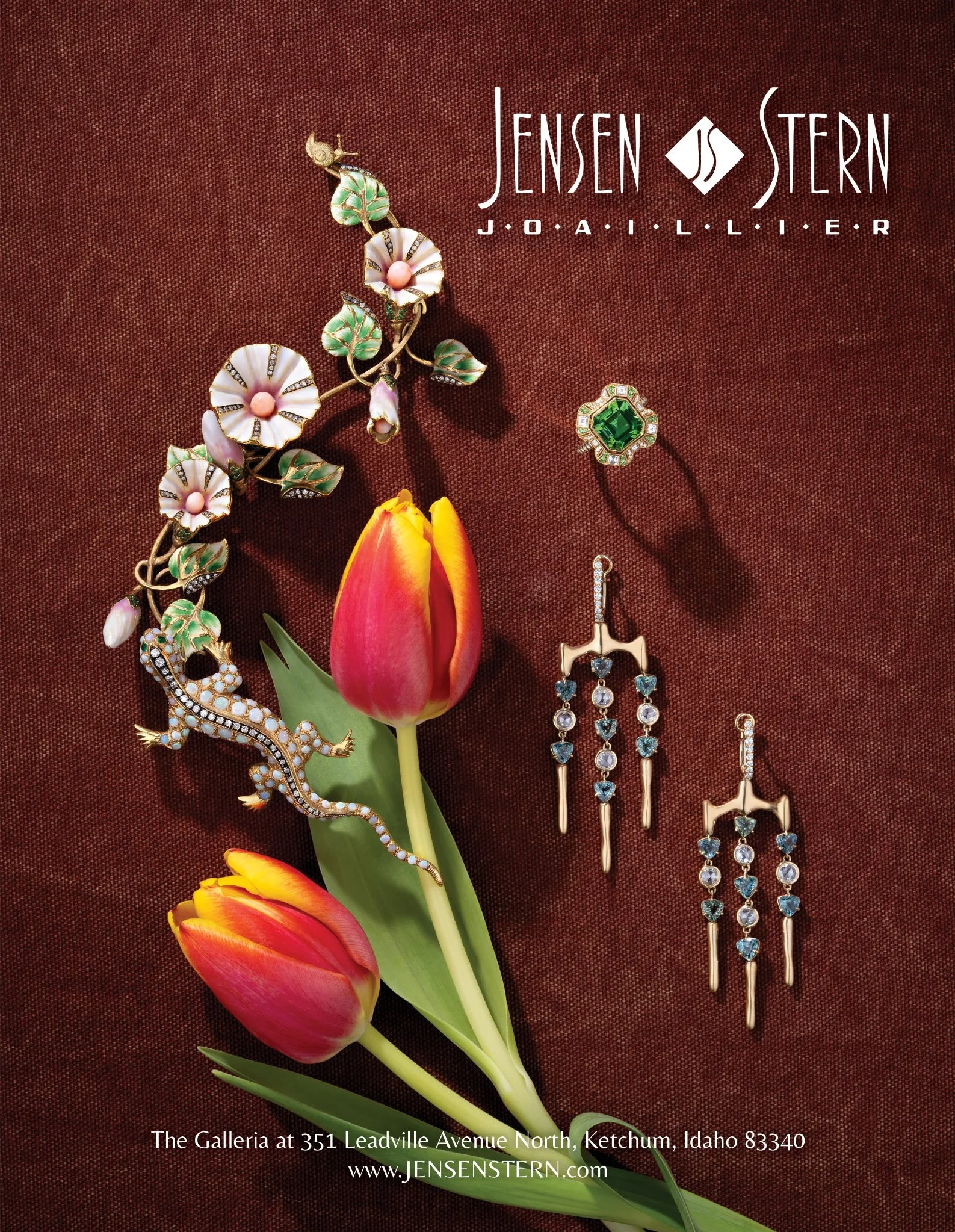 Display of jewelry including a floral brooch, emerald and diamond earrings, and tulips on a dark red textured background with text about Jens Stern jewelry at Galleria, Ketchum, Idaho.