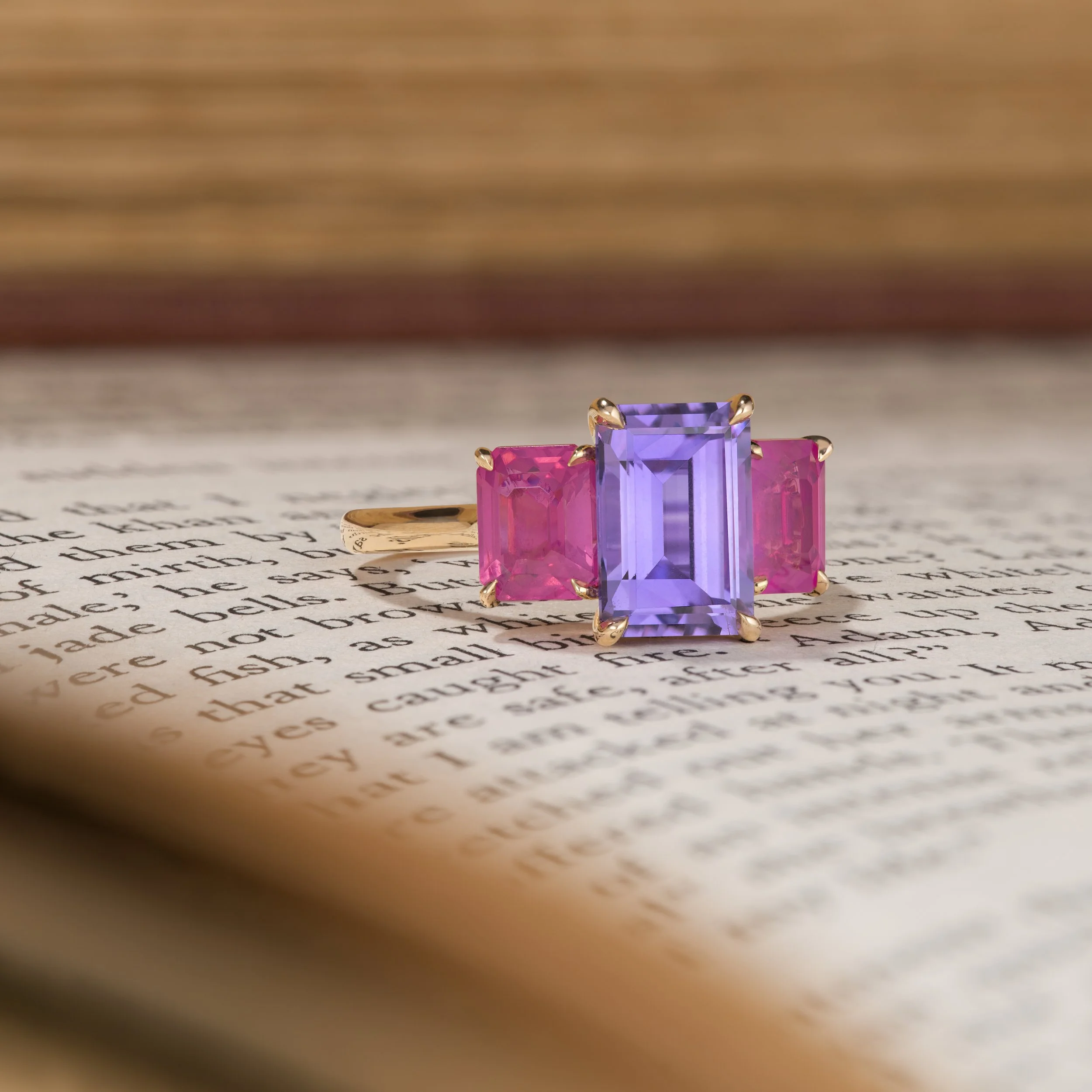 Purple and Pink Sapphire three stone ring on a book