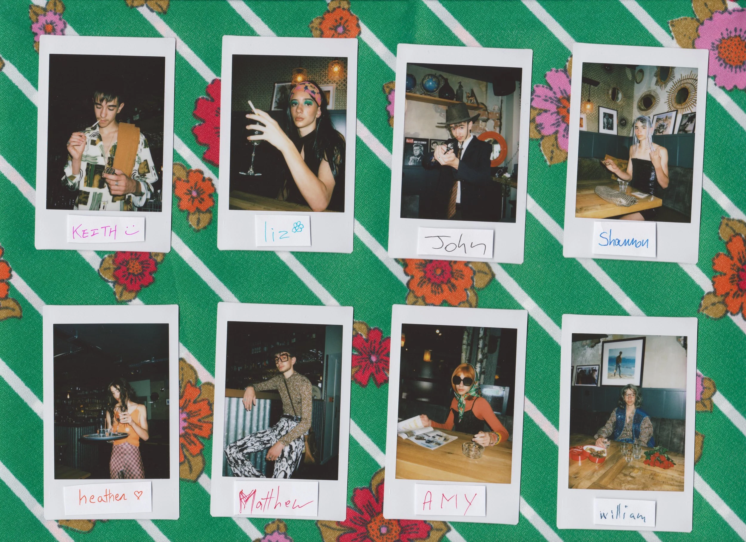 Une collection de huit photographies Polaroid de différentes personnes, chaque photo porte un nom écrit à la main : Keith, Liz, John, Shannon, Heather, Matthew, Amy, William, disposées sur un tissu vert à rayures avec des motifs de fleurs orange et roses.