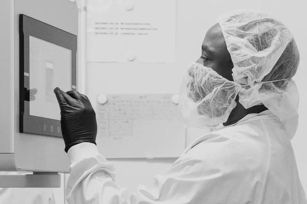An operator in full cleanroom gear operating a machine