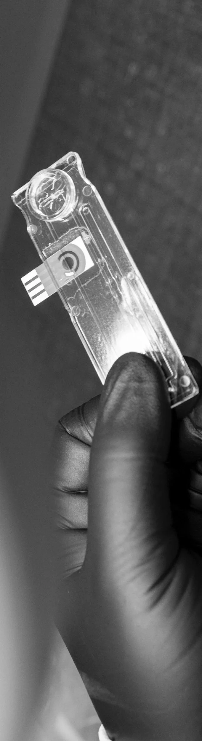 A hand holding a small transparent microfluidic disposable with integrated electro-chemical detection electrodes