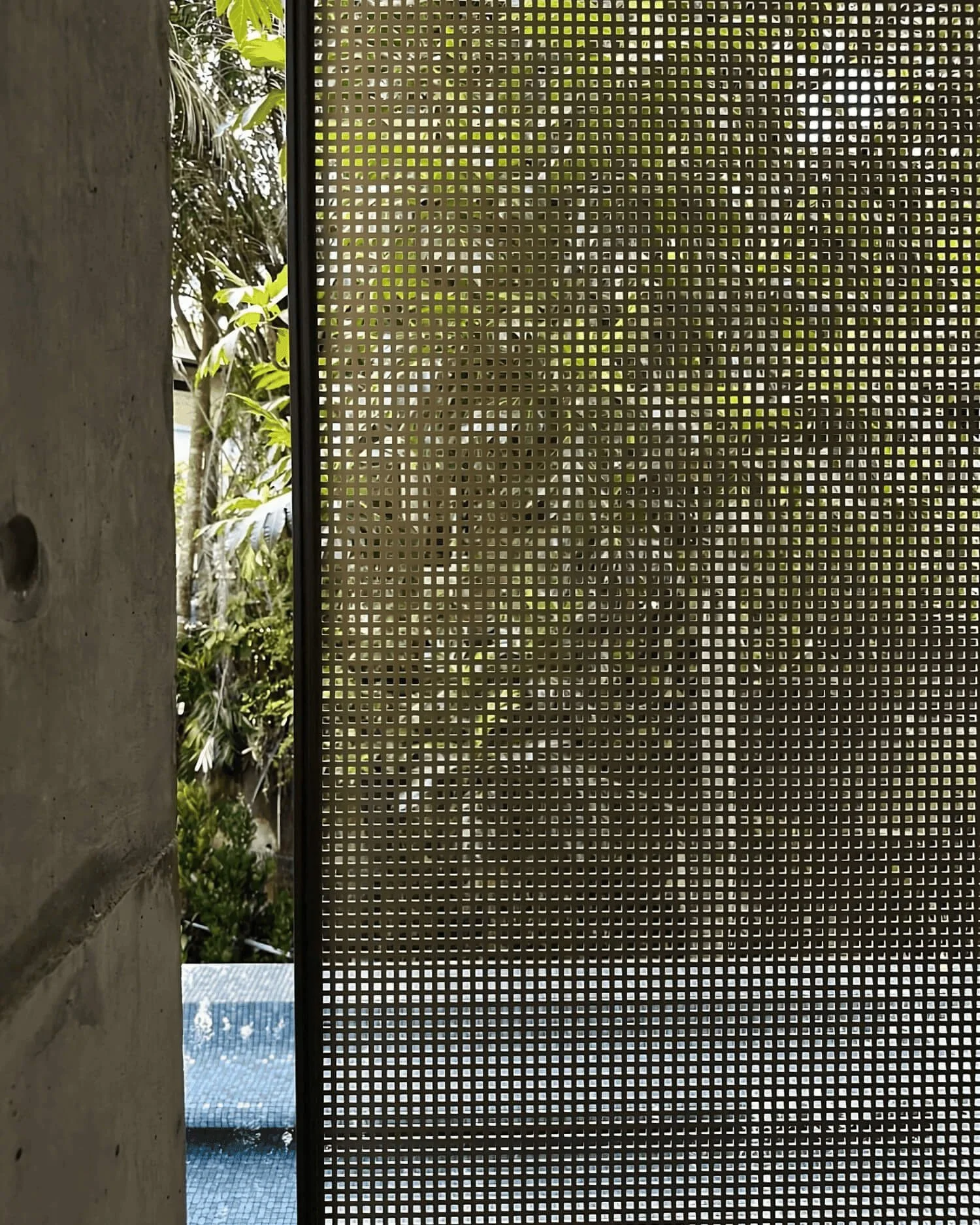 Perforated screen façade at Ford Avenue GCB, featuring precision square perforations that filter natural light, enhance privacy, and frame lush tropical landscaping.