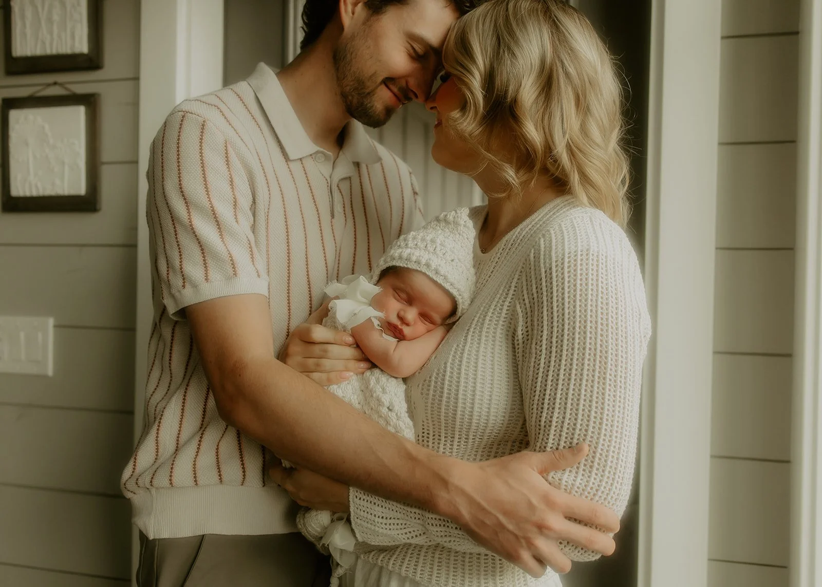 Two parents snuggling their newborn baby girl in their house.