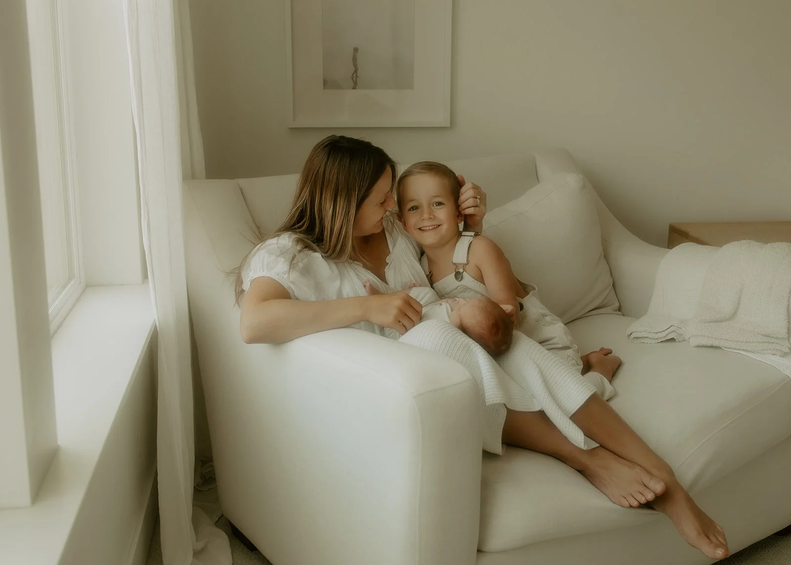 A mother sitting on a large chaise with her two you children.