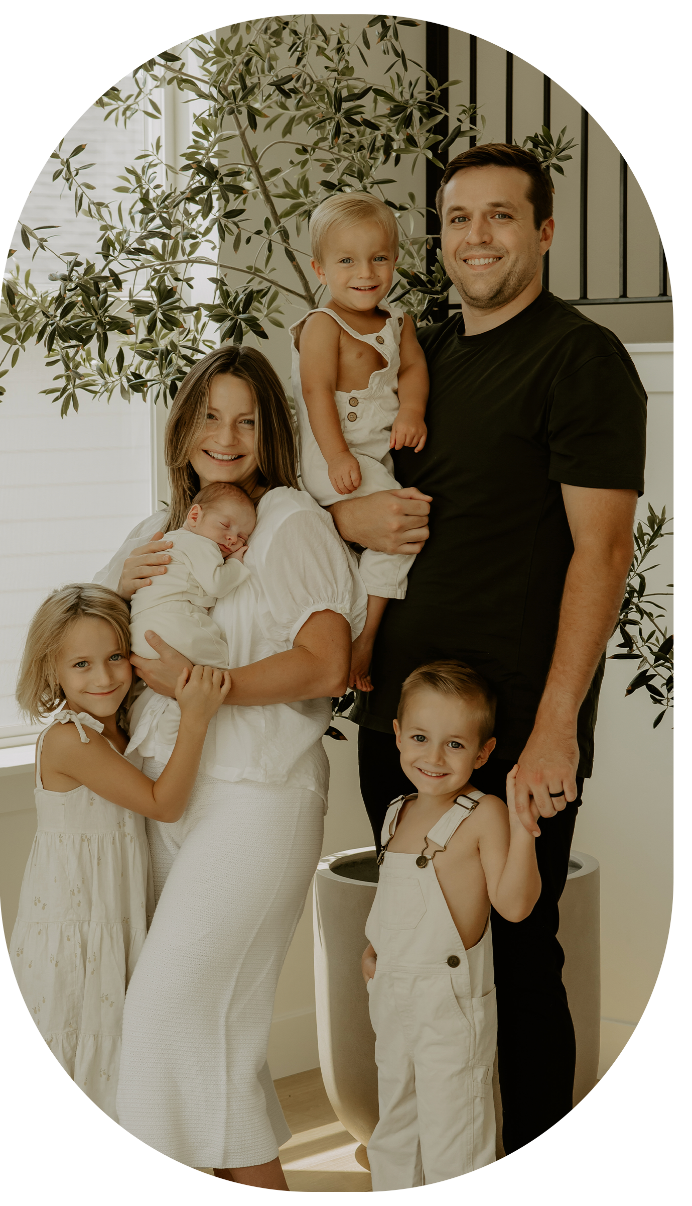 A family standing inside their home holding hands and smiling