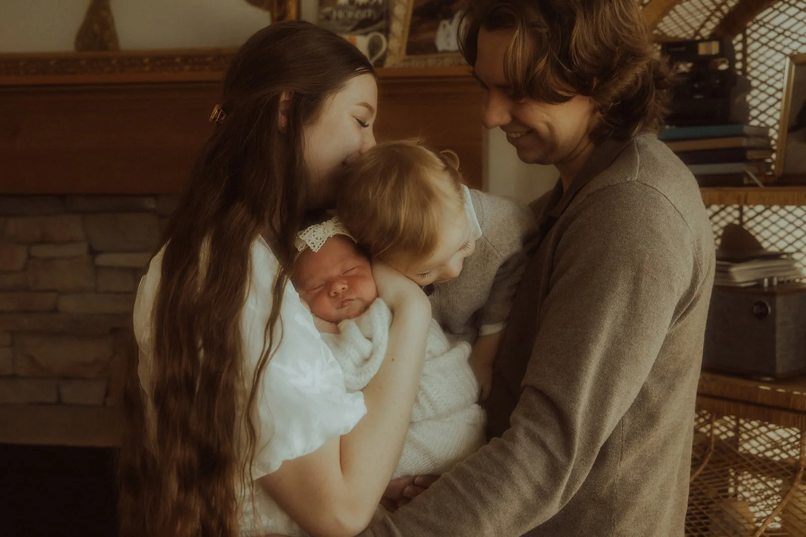 A family of four snuggling together in their home with their newborn baby girl.