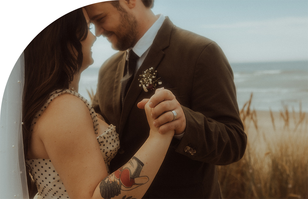 A couple standing on the beach embracing each other after their wedding ceremony.