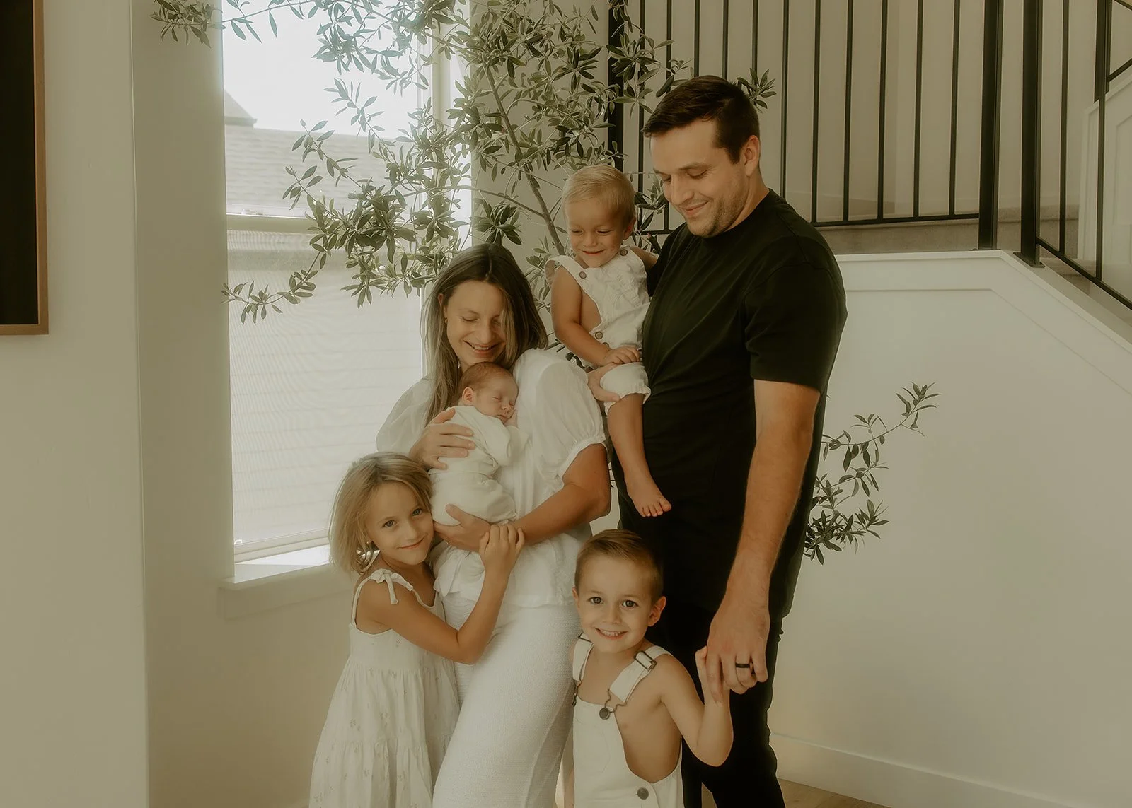 A family of six standing in their home and smiling at one another.