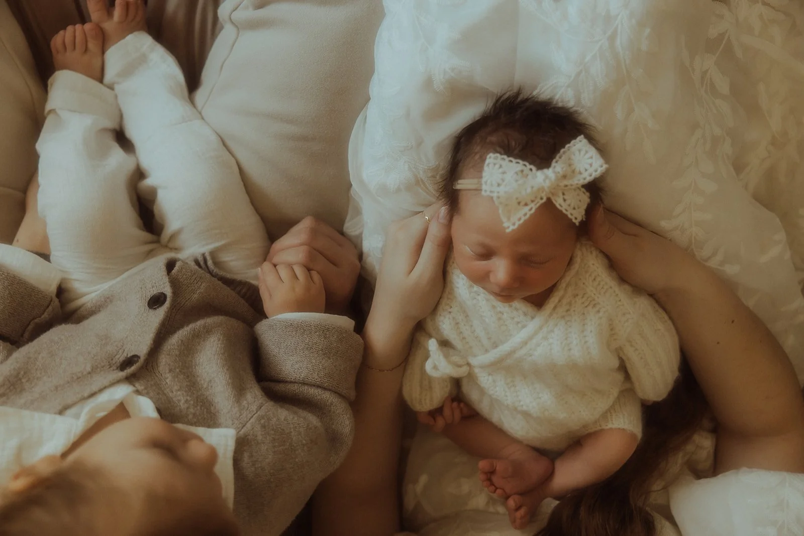 A little boy sitting next to his newborn sister.