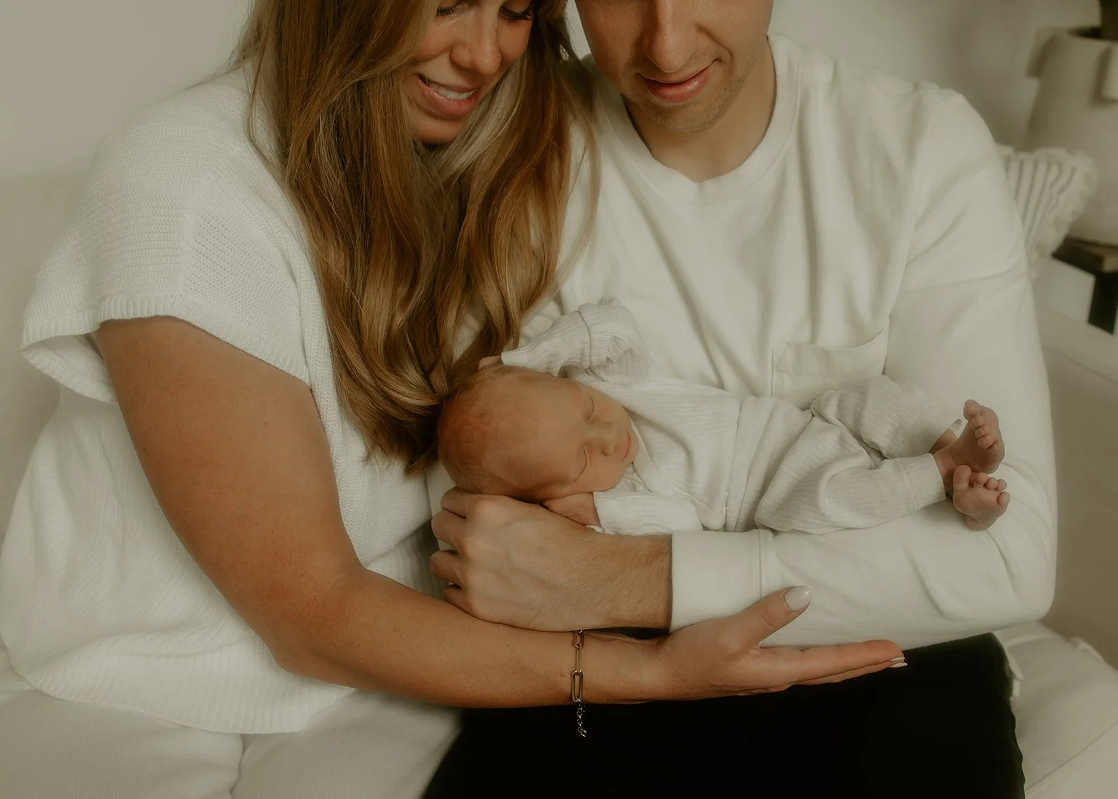 Two parents cradling their newborn baby and smiling down at him.