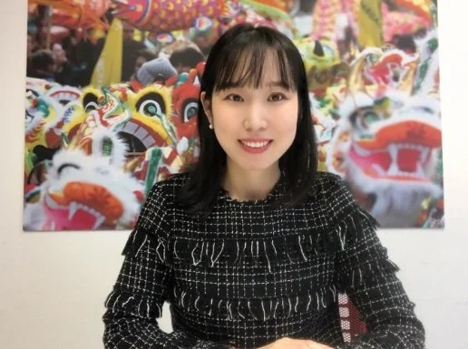 Person, die vor einem farbenfrohen Kunstwerk mit Drachenmotiven sitzt